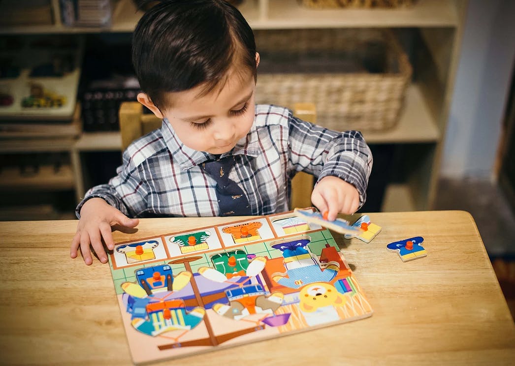 Child playing with a puzzle on a wooden table