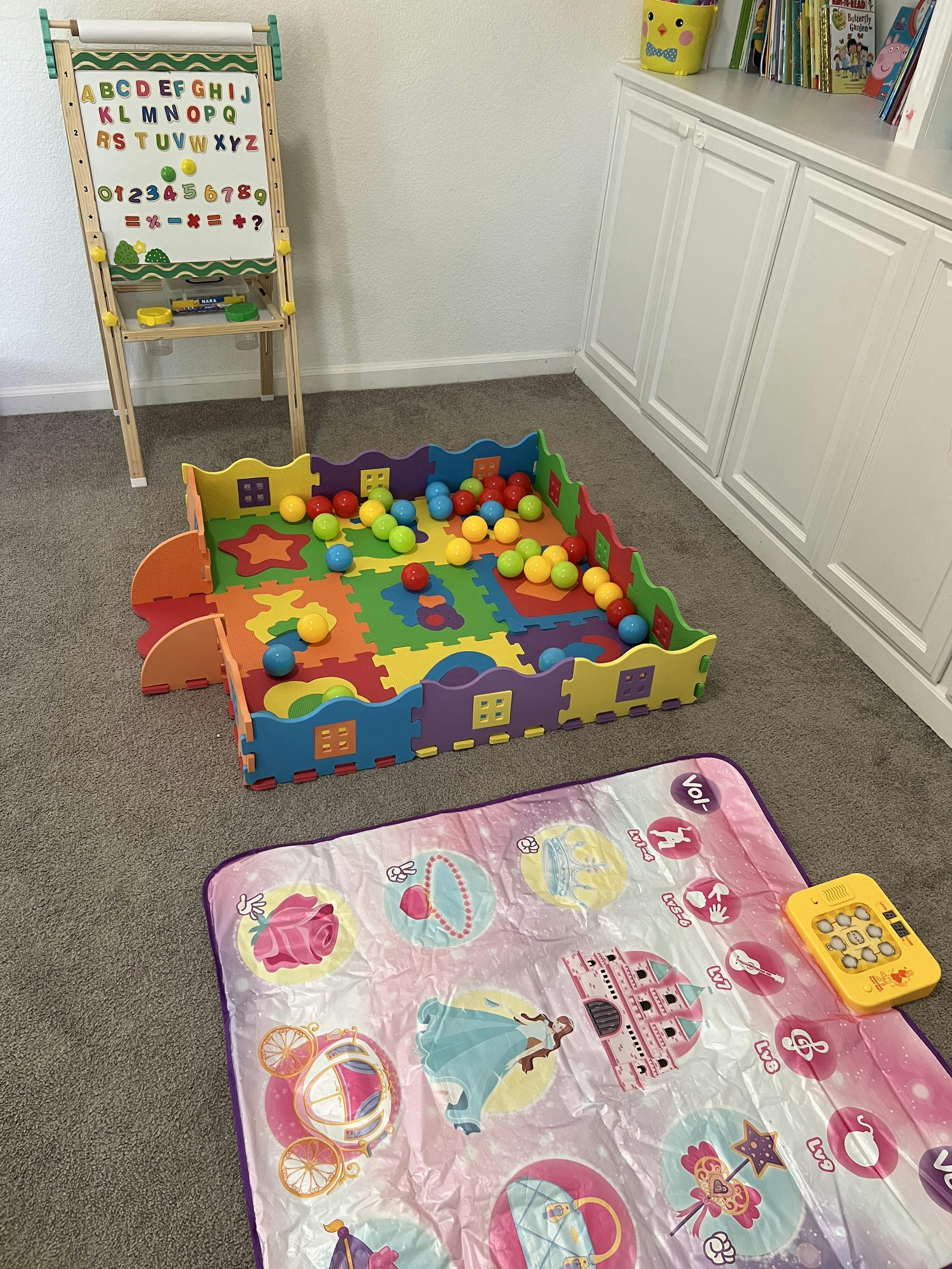 Playroom with a ball pit, easel, and playmat