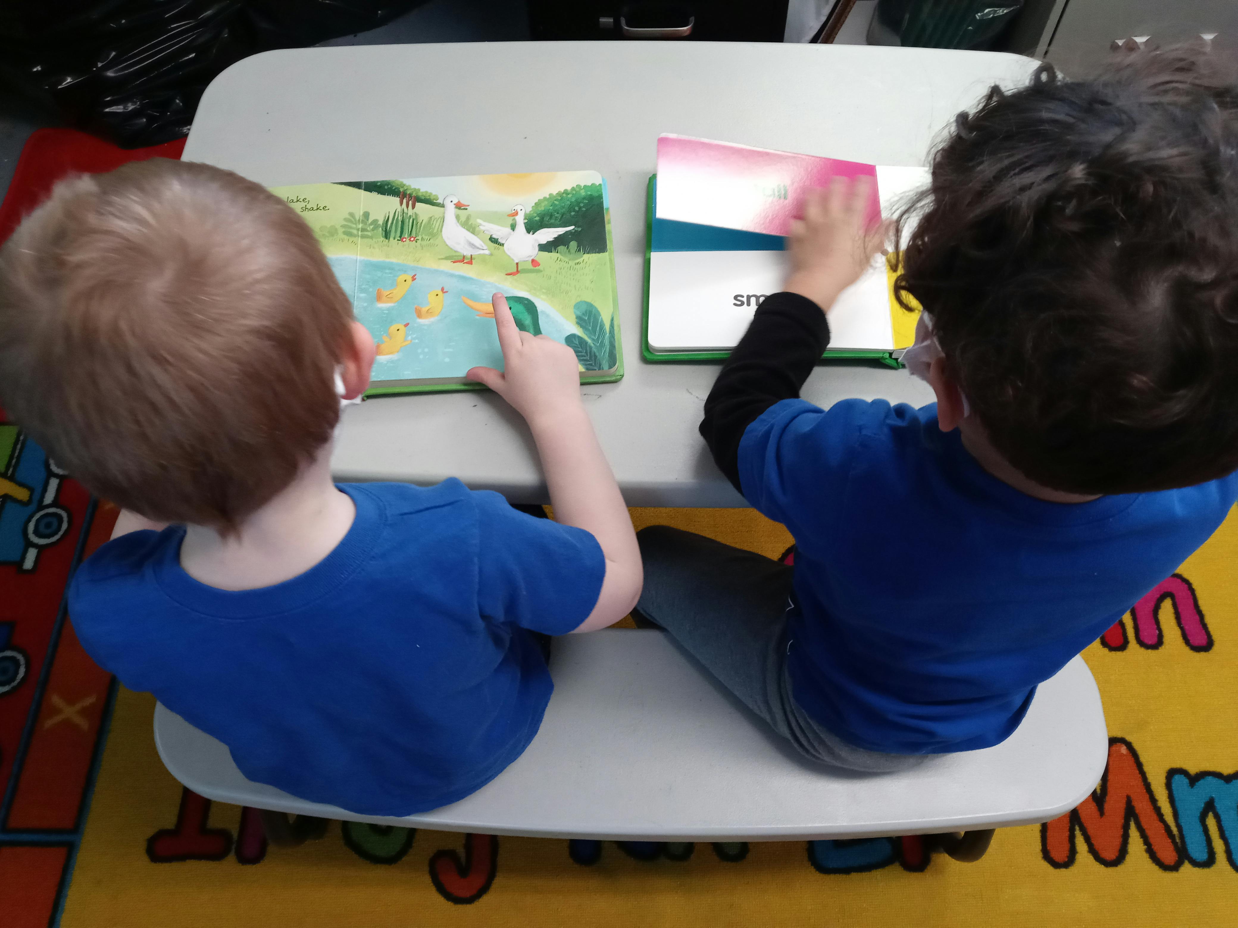 Two children sitting at a desk, reading books