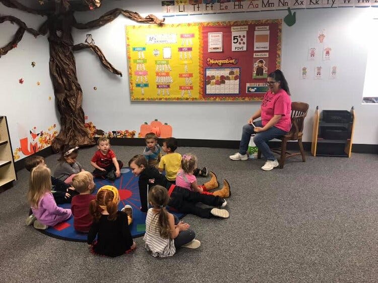 Adult reading to children sitting on a rug in a classroom