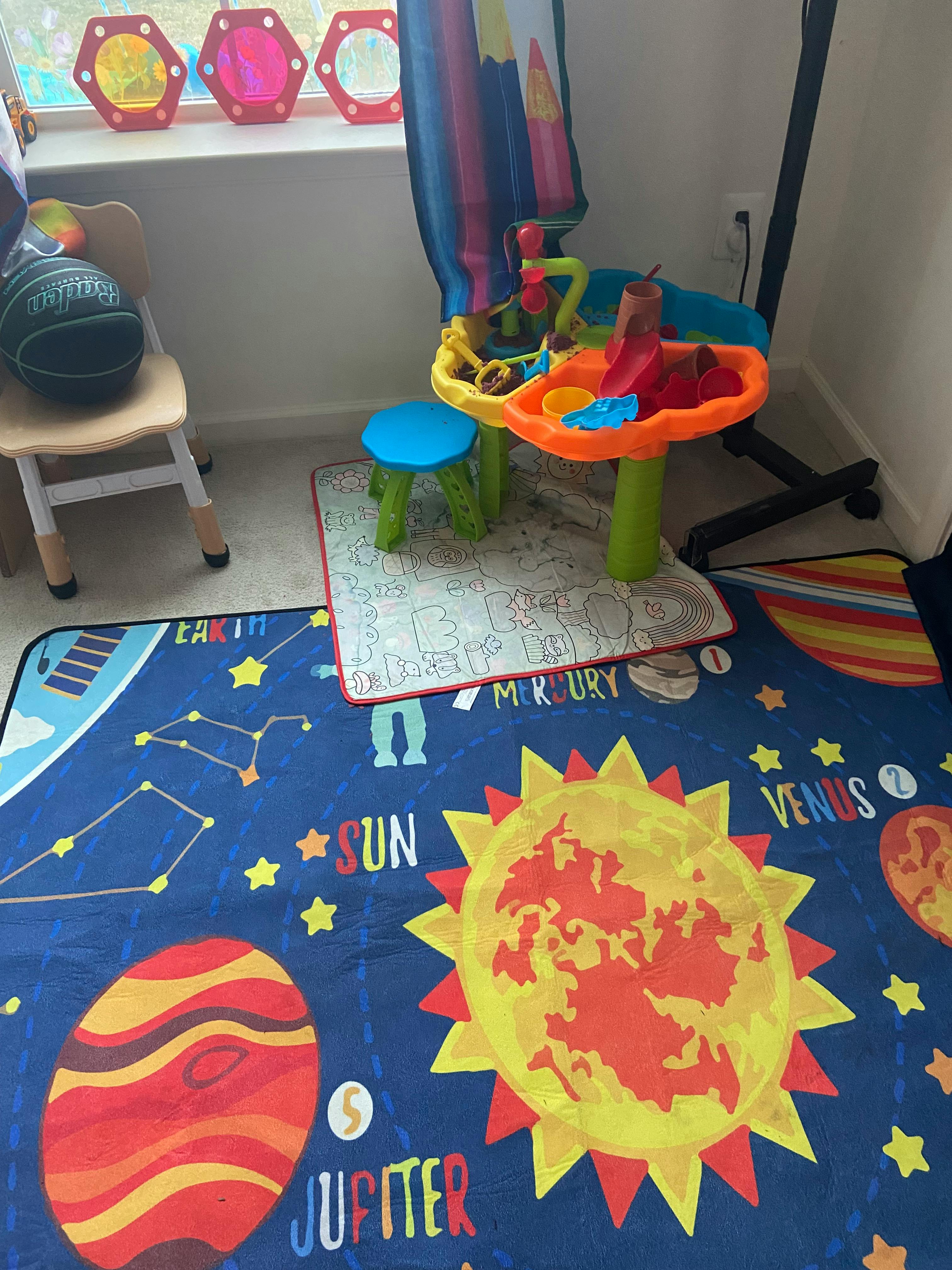 Children's play area with a solar system rug and colorful activity center