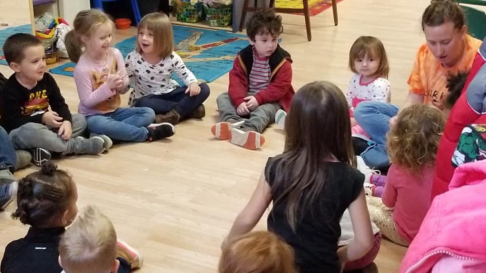 Children and an adult sitting in a circle on the floor