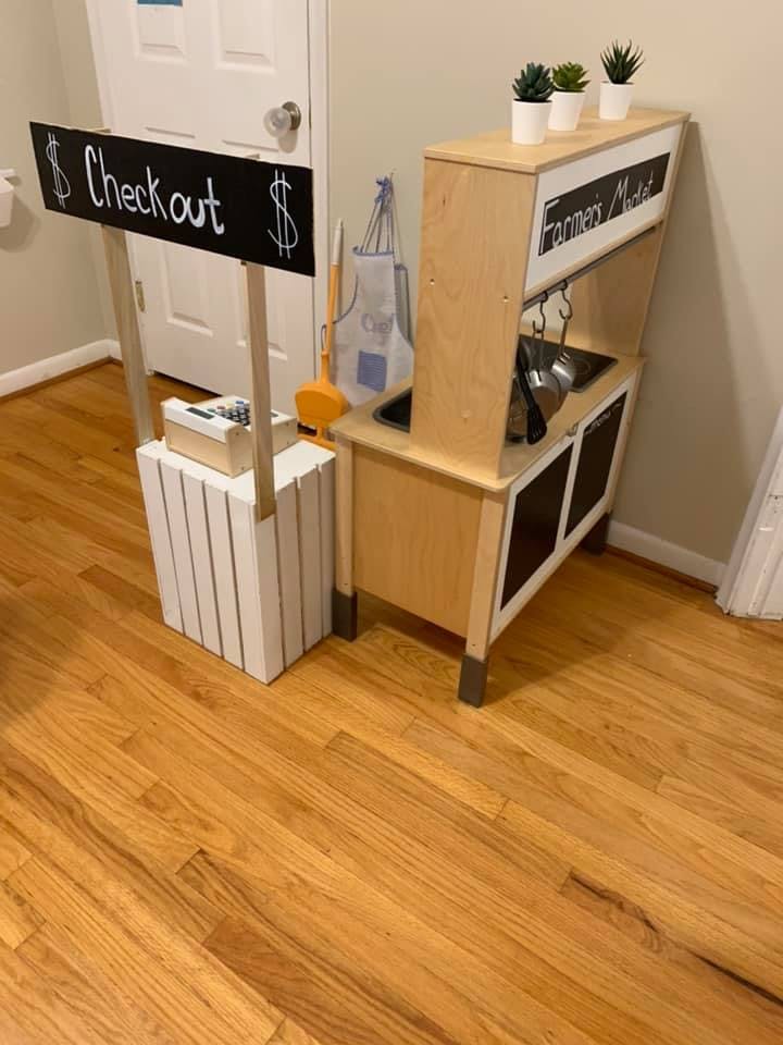 Toy checkout stand with a "Checkout" sign and a toy kitchen set with a "Farmers Market" sign
