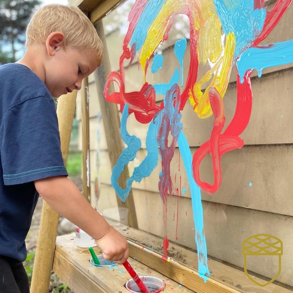 Child painting on a clear easel with colorful paint