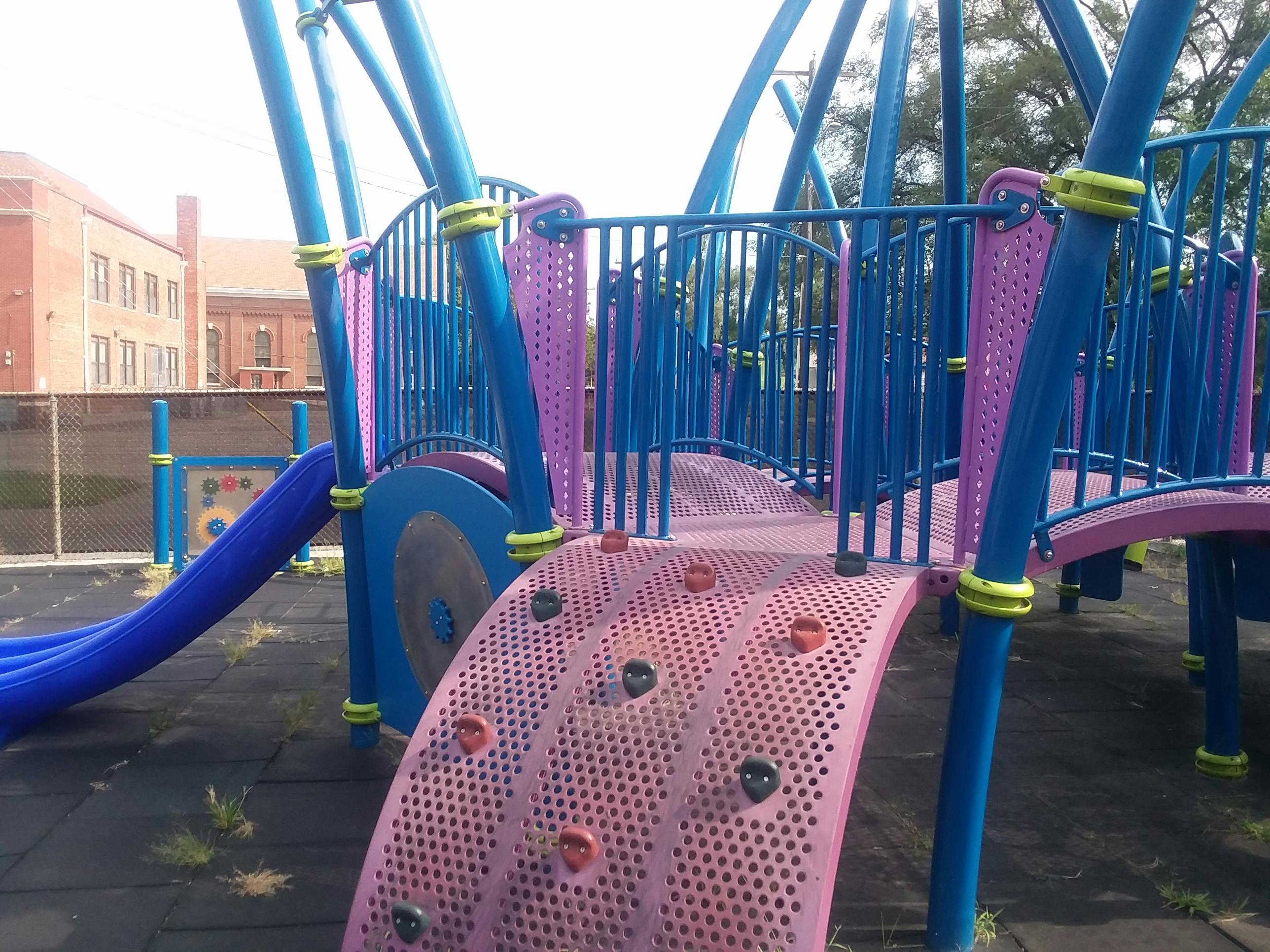 Playground structure with blue slides and pink climbing wall
