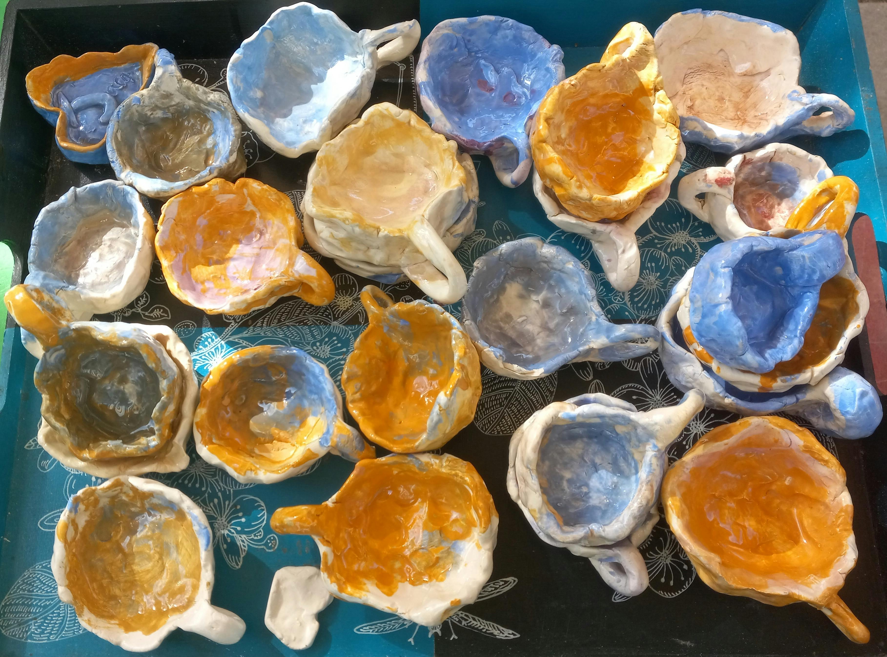 Group of handmade ceramic cups with yellow and blue glaze on a decorative tray