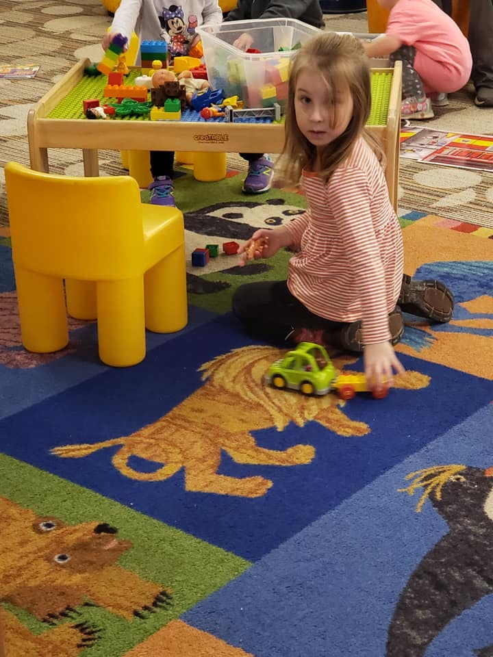 Child playing with a toy car on a rug