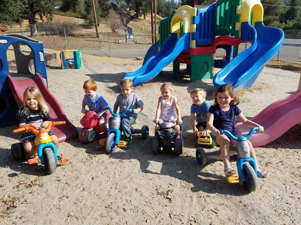 Five children on tricycles on a playground