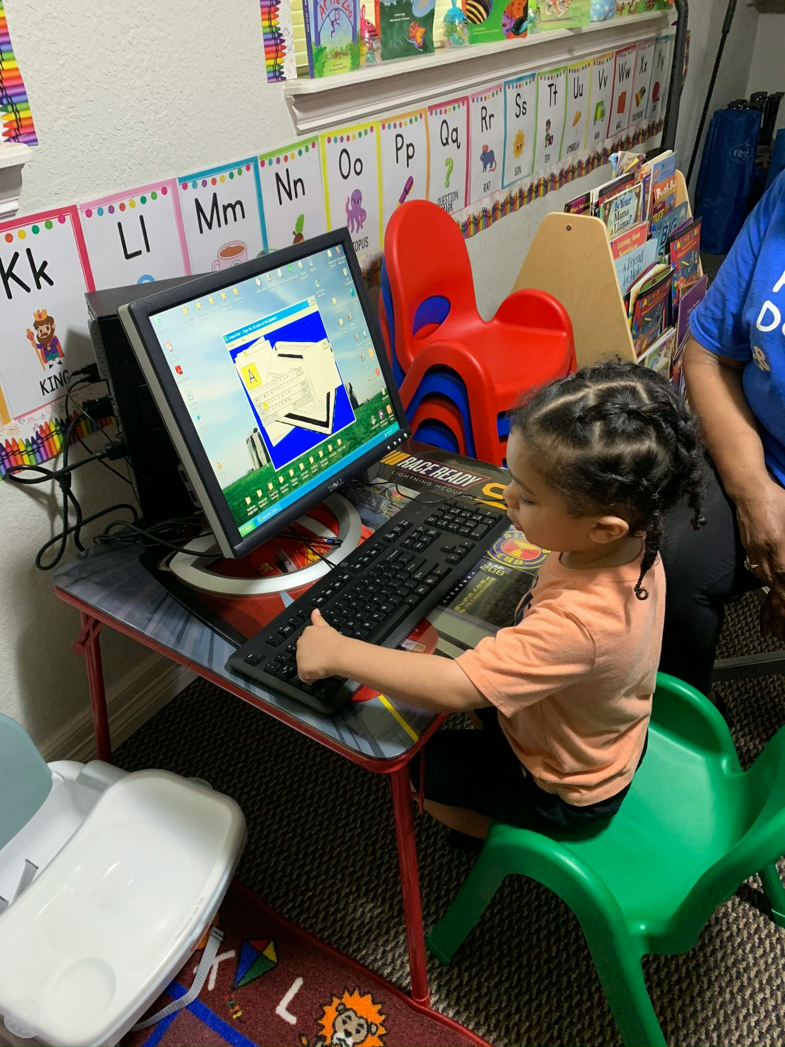 Child sitting at a small desk using a computer keyboard