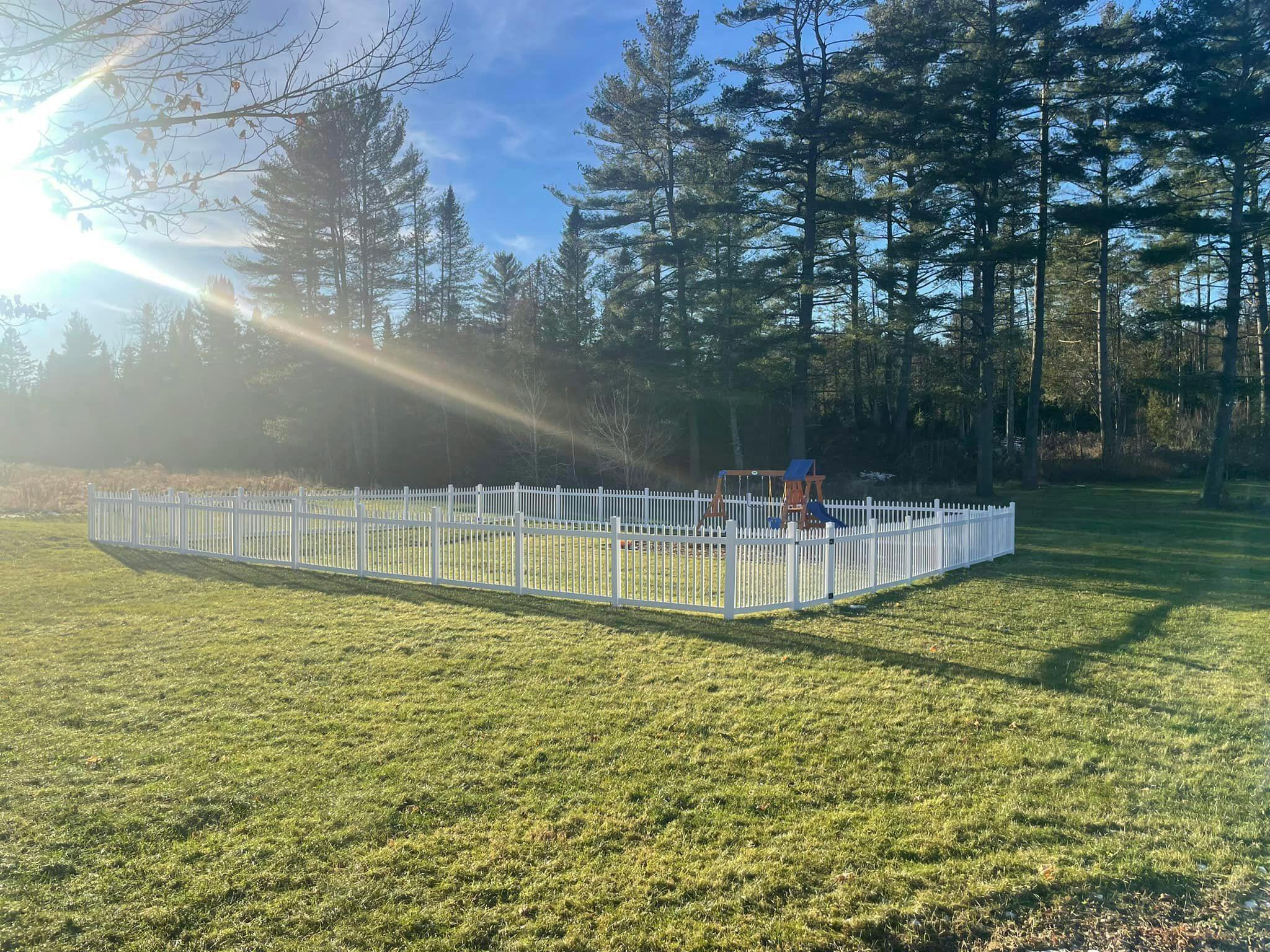 White fence enclosing a playground on a grassy field