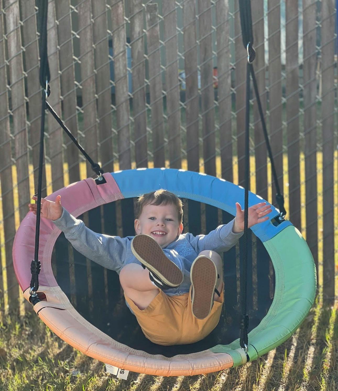 Child smiling and sitting in a circular swing