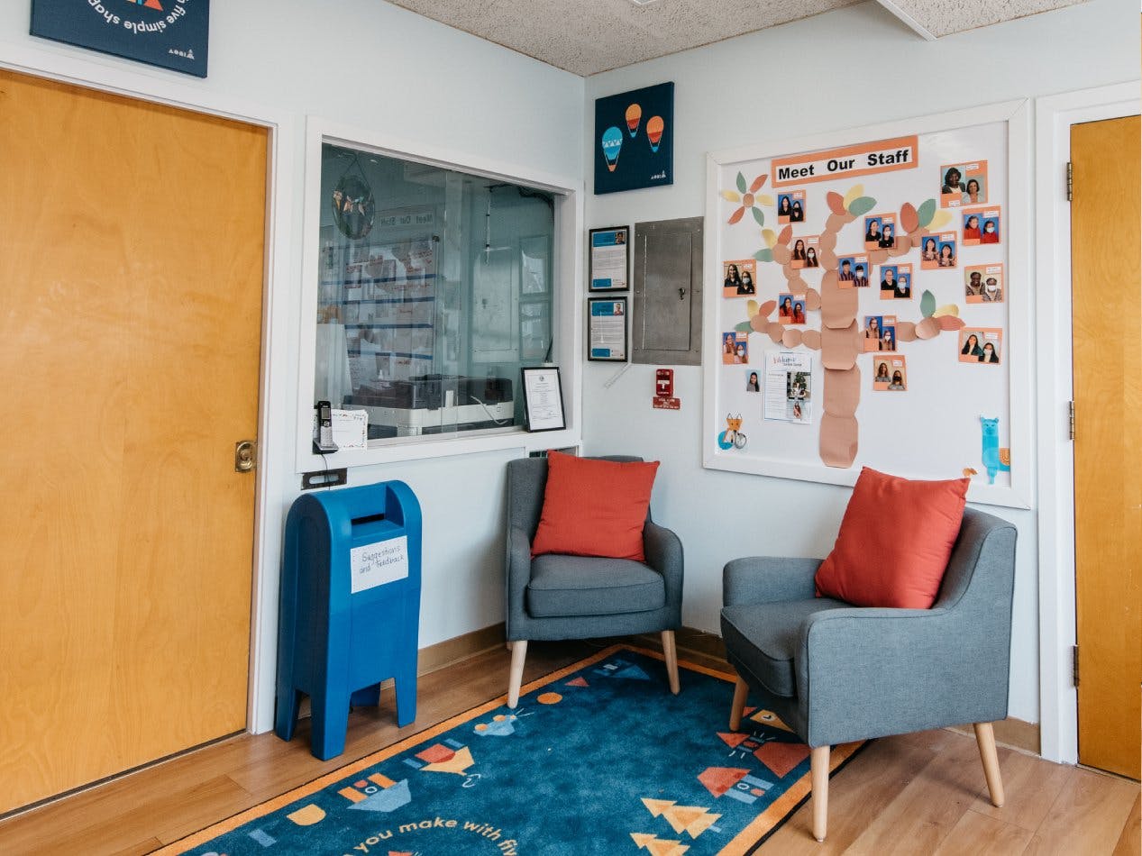 Lobby area with a "Meet Our Staff" board, two chairs, and a blue suggestion box