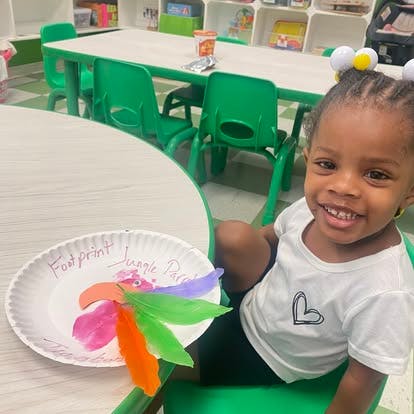Child sitting at a table with a paper plate craft