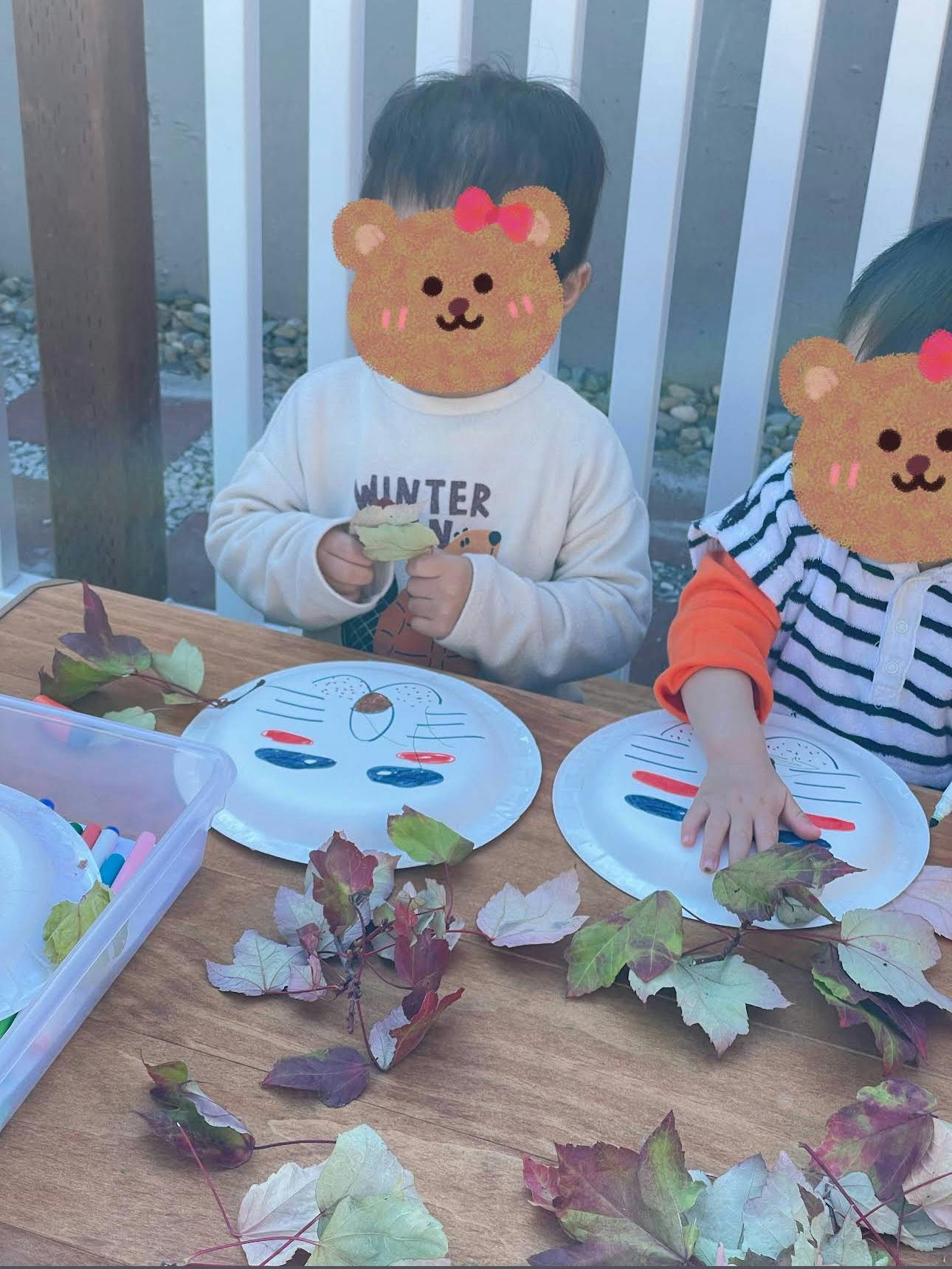 Two children at a table with leaves and paper plates