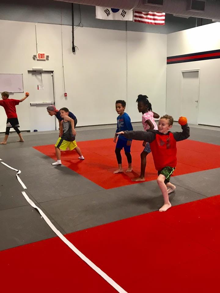 Children and adults playing dodgeball in a gym