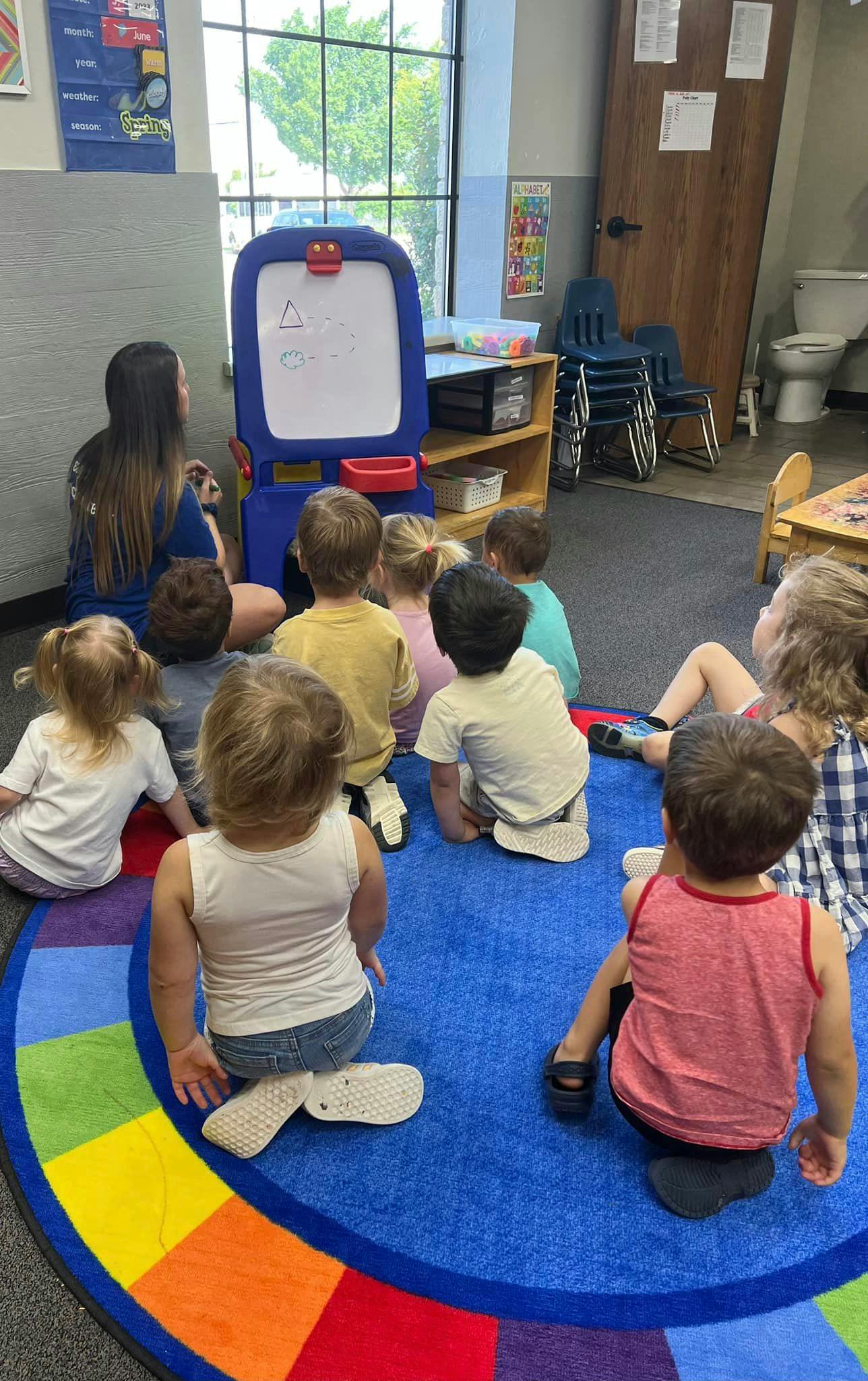 Adult and children sitting on a rug in a classroom