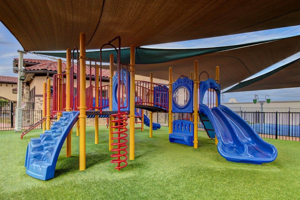 Playground with slides, climbing structures, and shade sails overhead shade sails