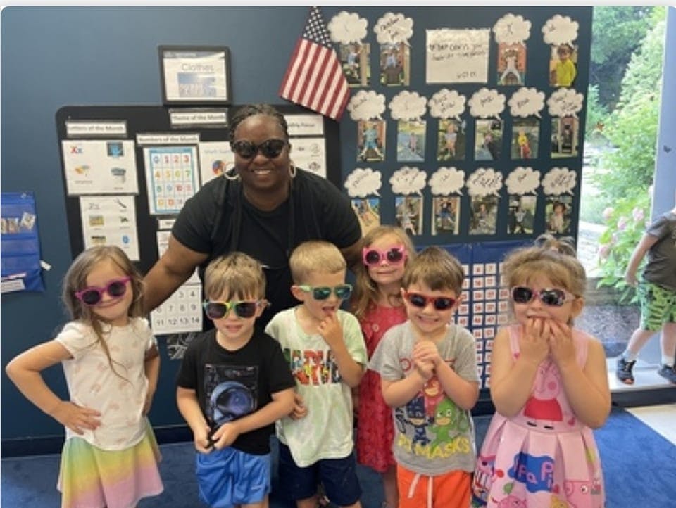 Adult and multiple children wearing sunglasses in a classroom