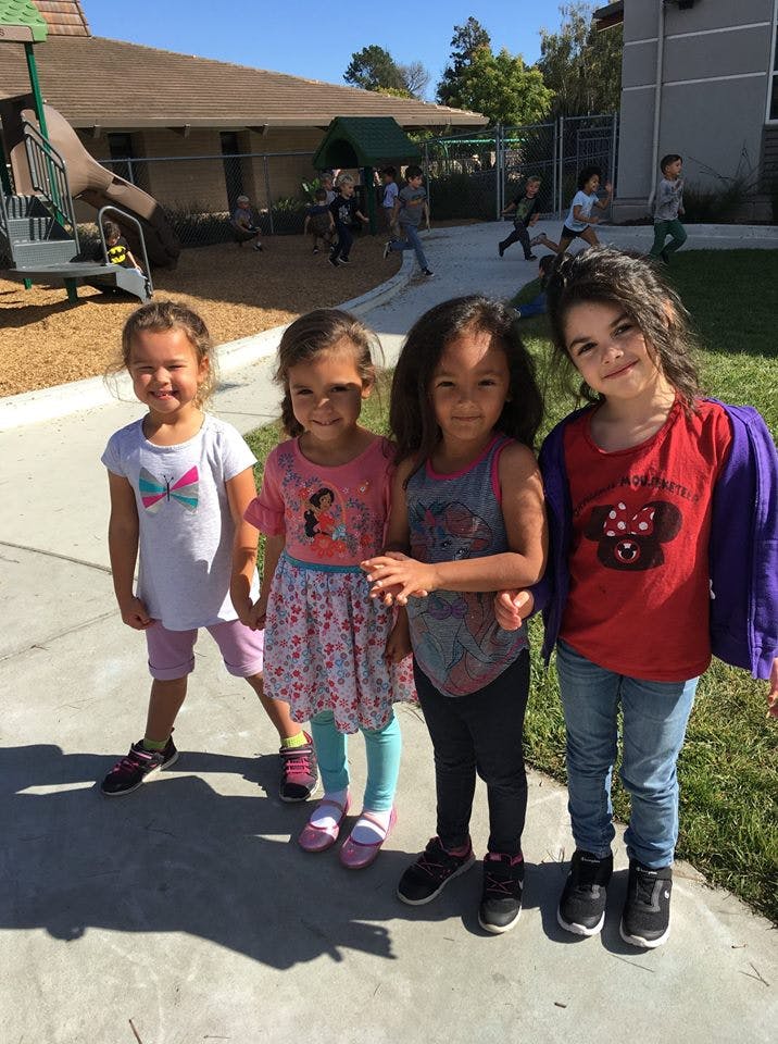 Four children standing together on a paved surface