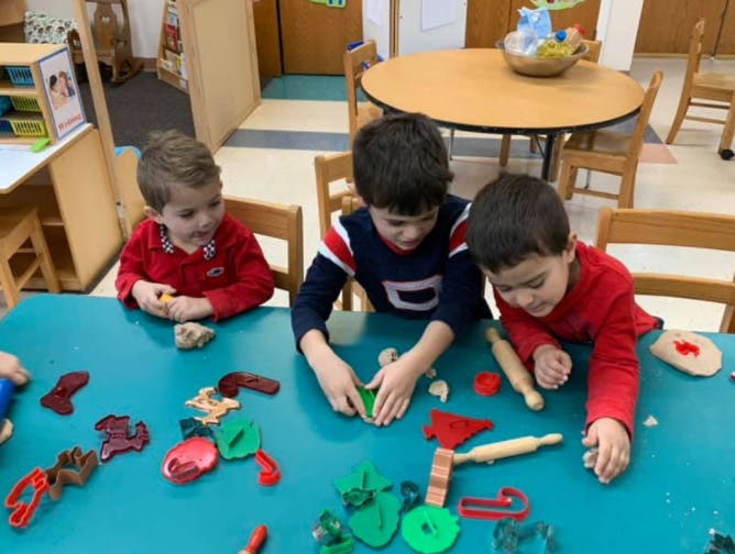 Three children playing with modeling clay at a table