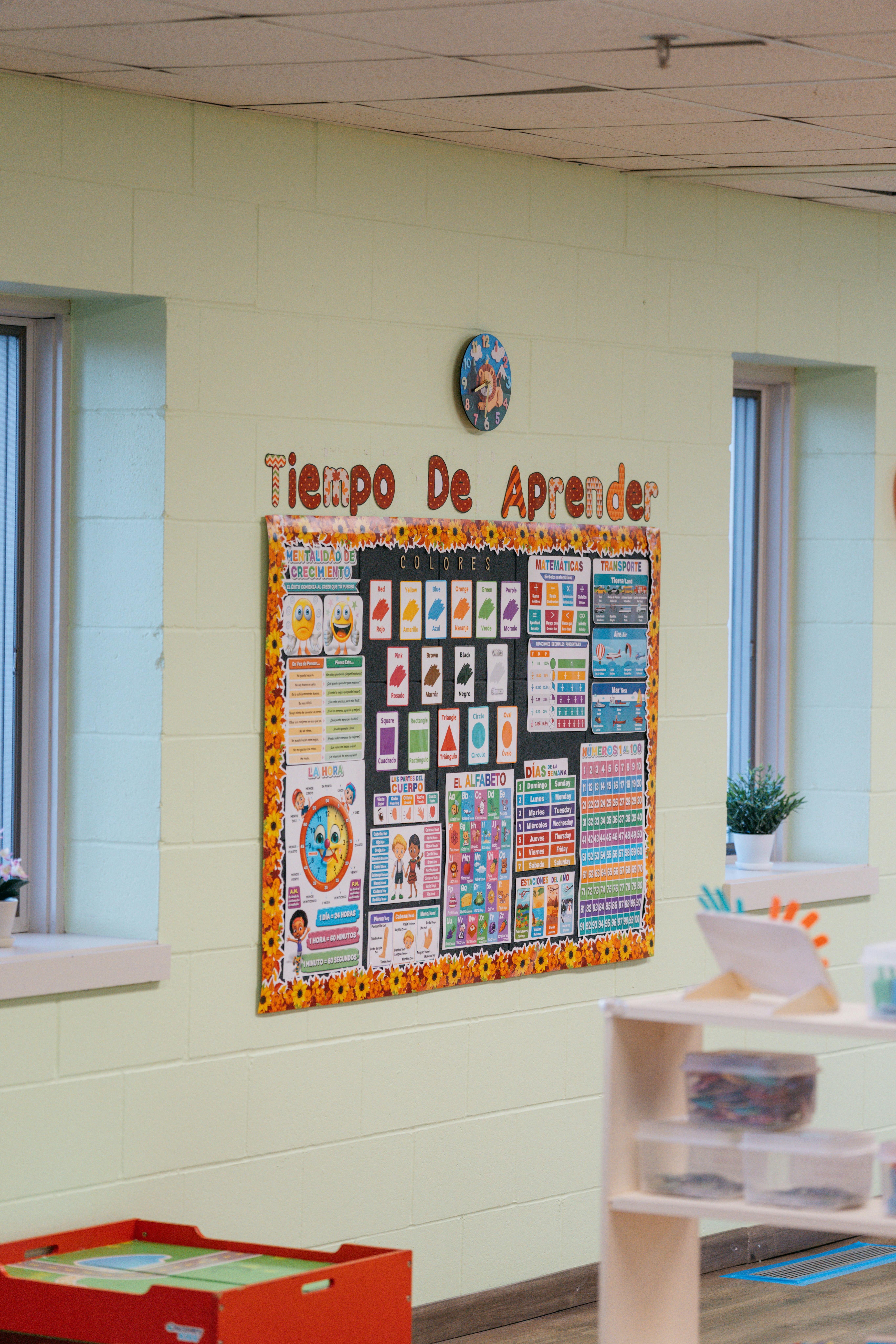 Bulletin board with colorful charts and text "Tiempo De Aprender" in a classroom