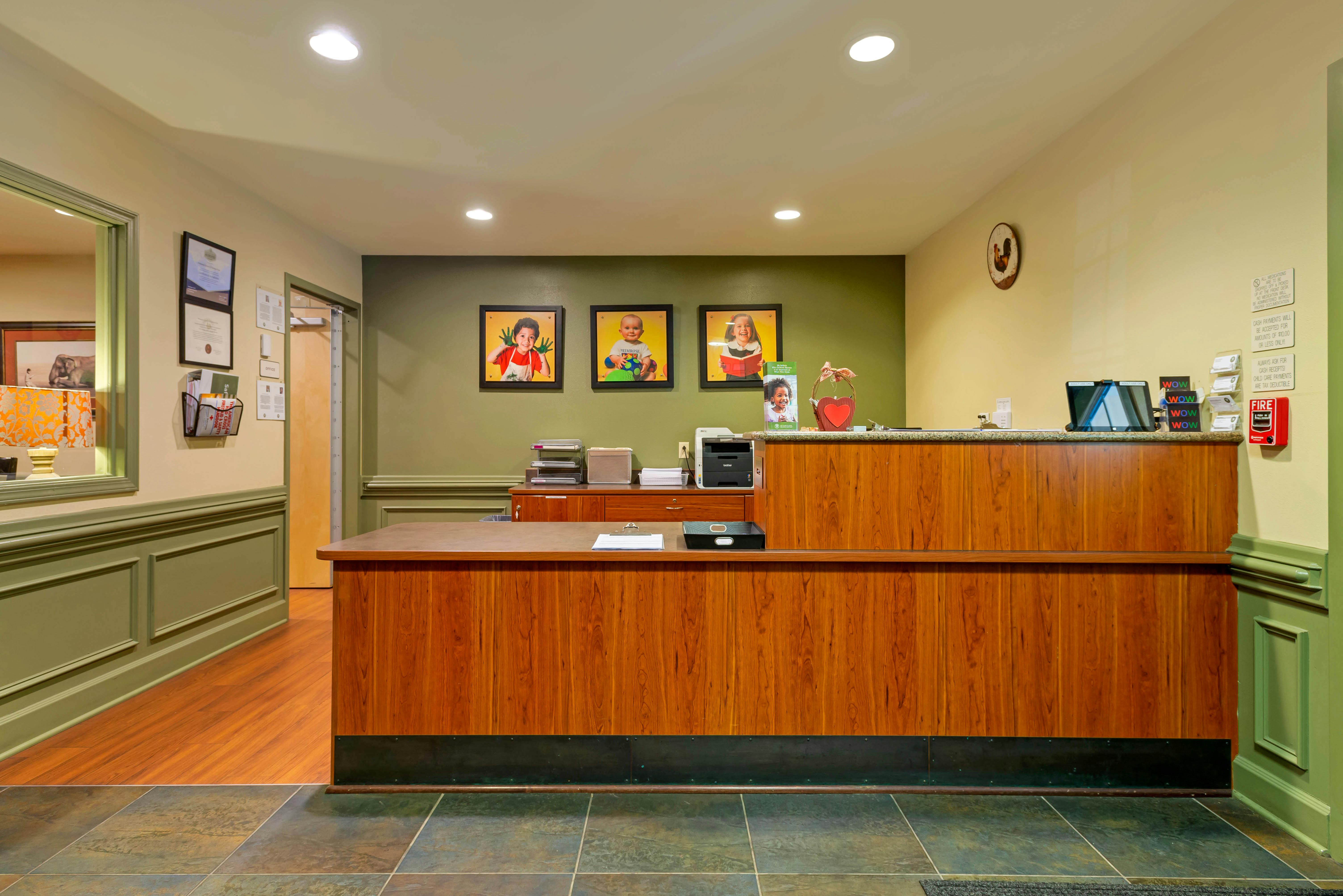Reception desk with wood paneling and three framed photos of children on the wall