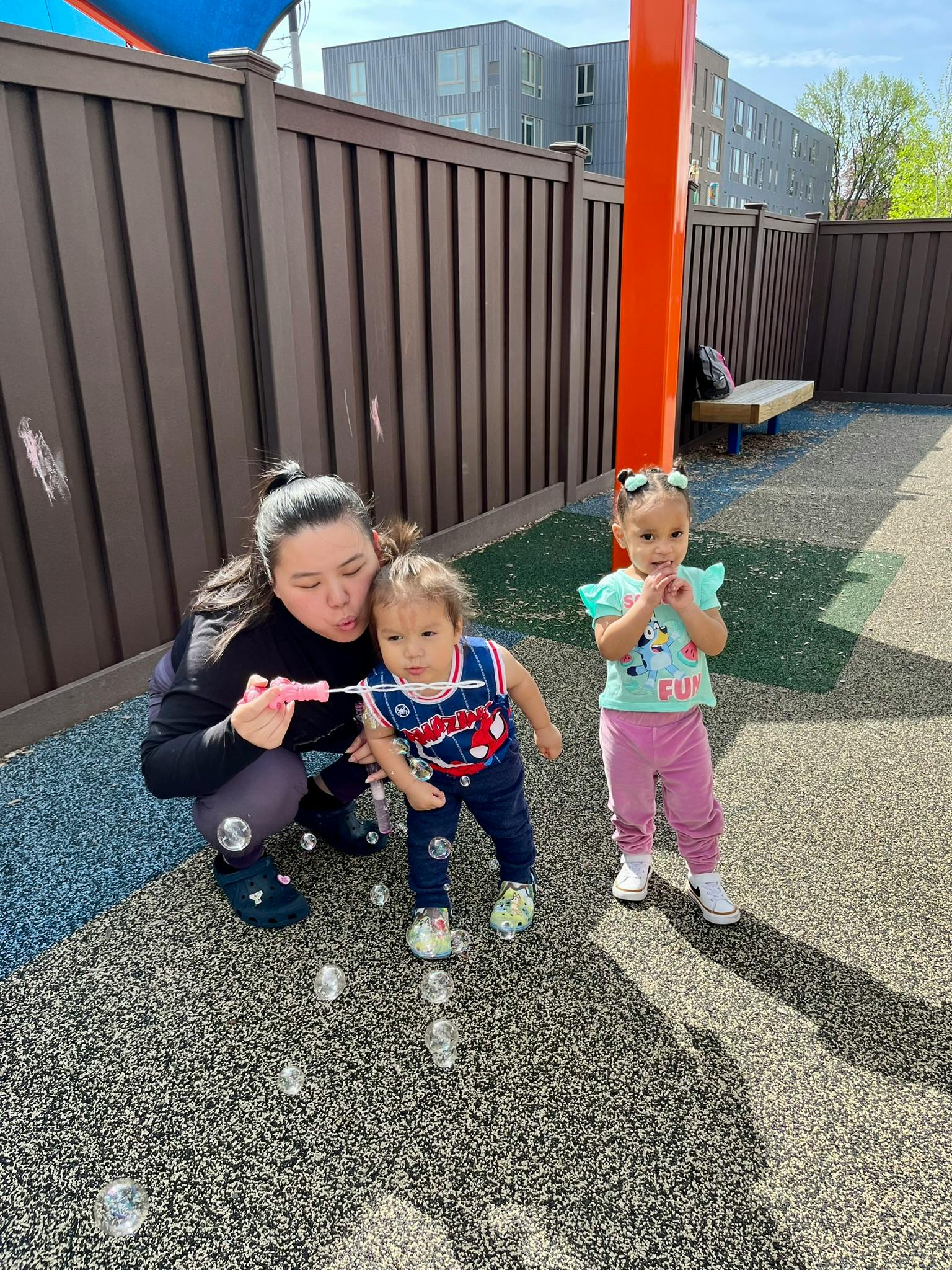 Person blowing bubbles for two children on a playground