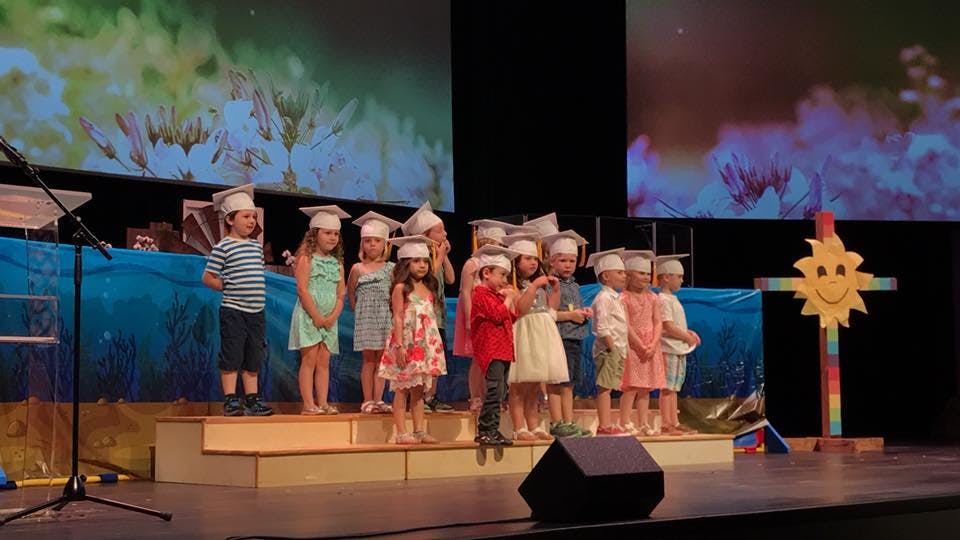 Children in graduation caps standing on a stage