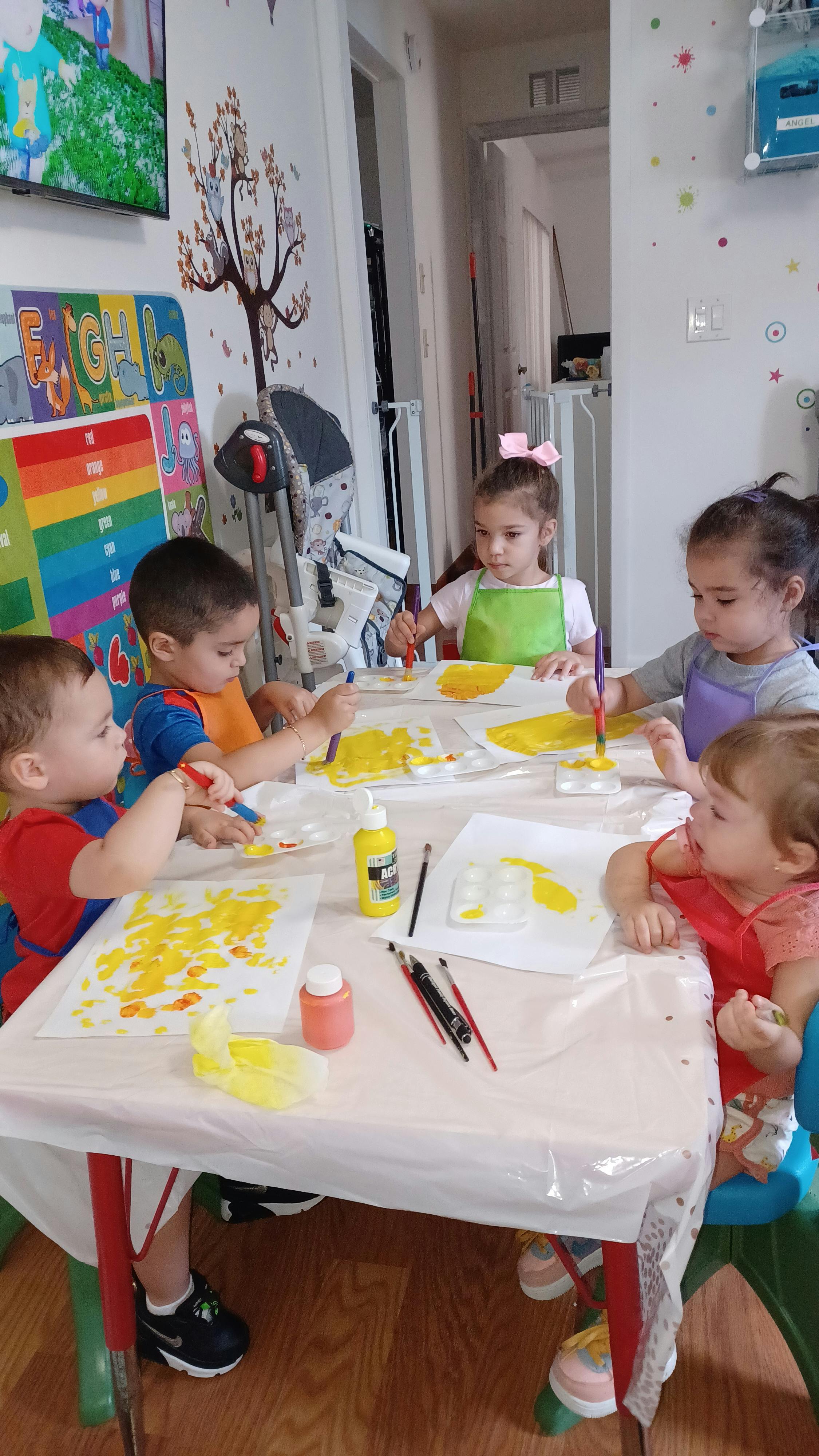 Four children painting at a table