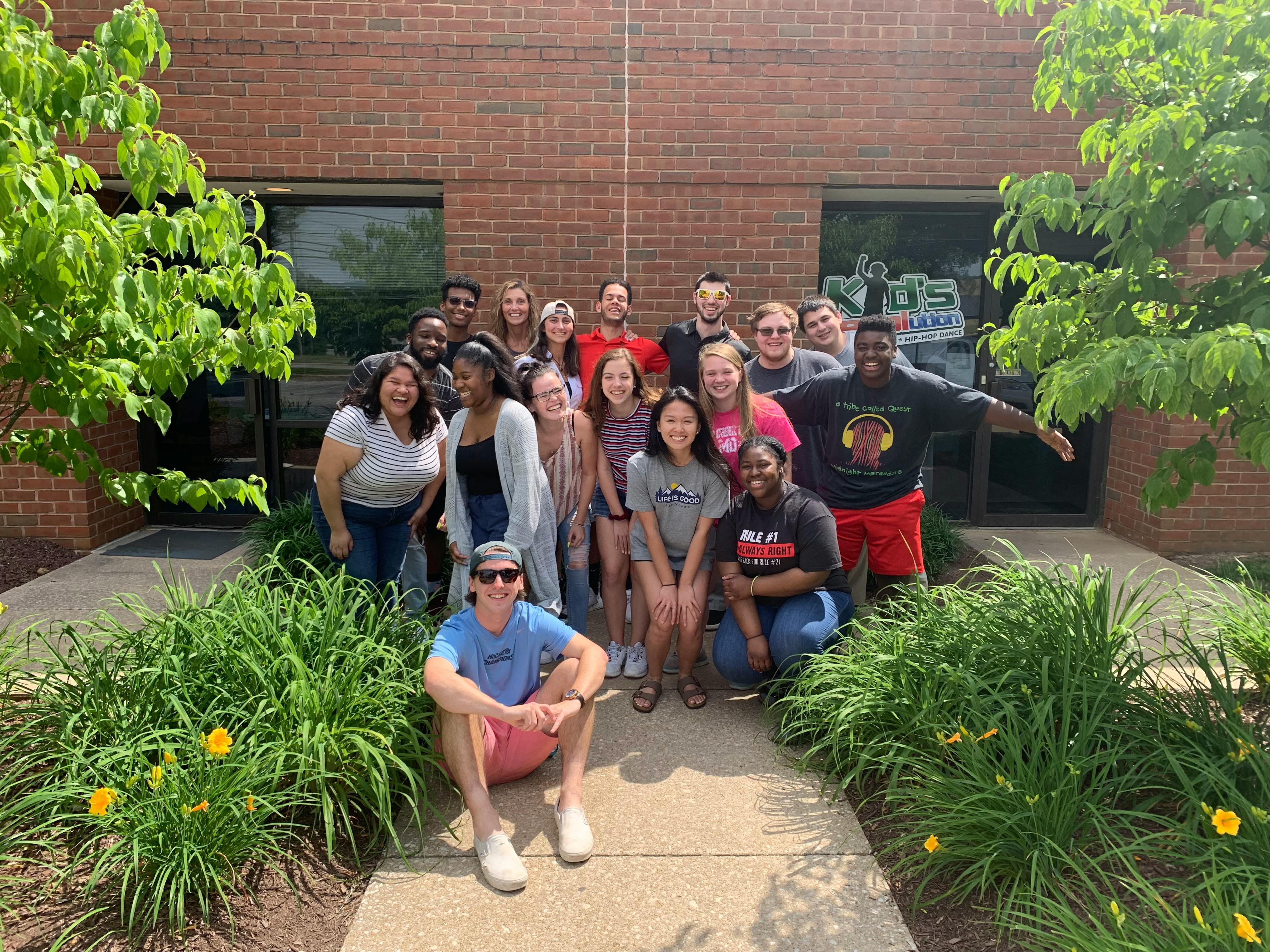 Group of people posing for a photo outdoors in front of a brick building
