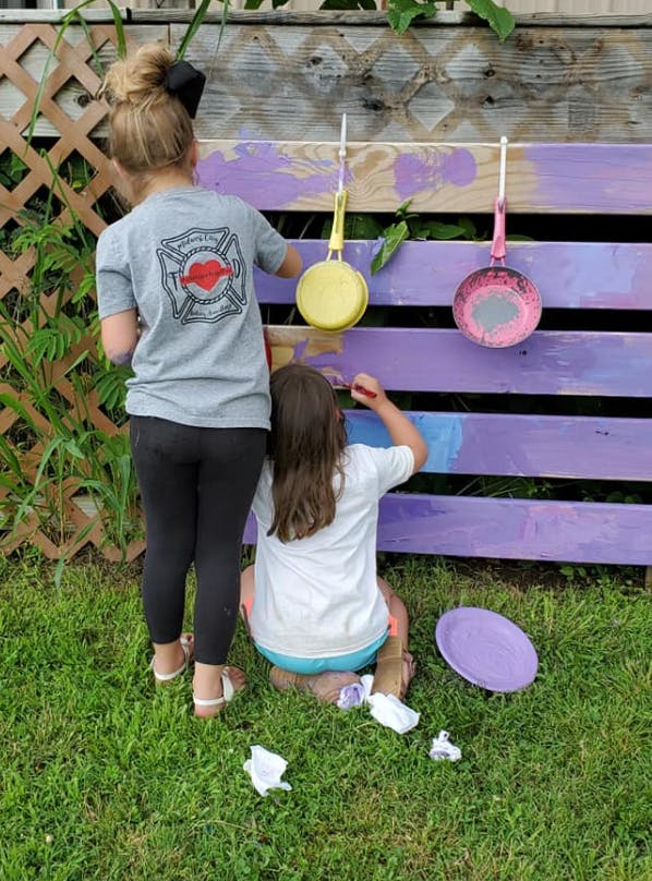 Two children painting a wooden fence