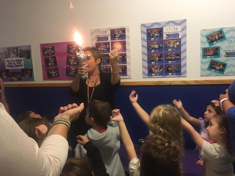 Person holding a flaming torch surrounded by children with raised hands
