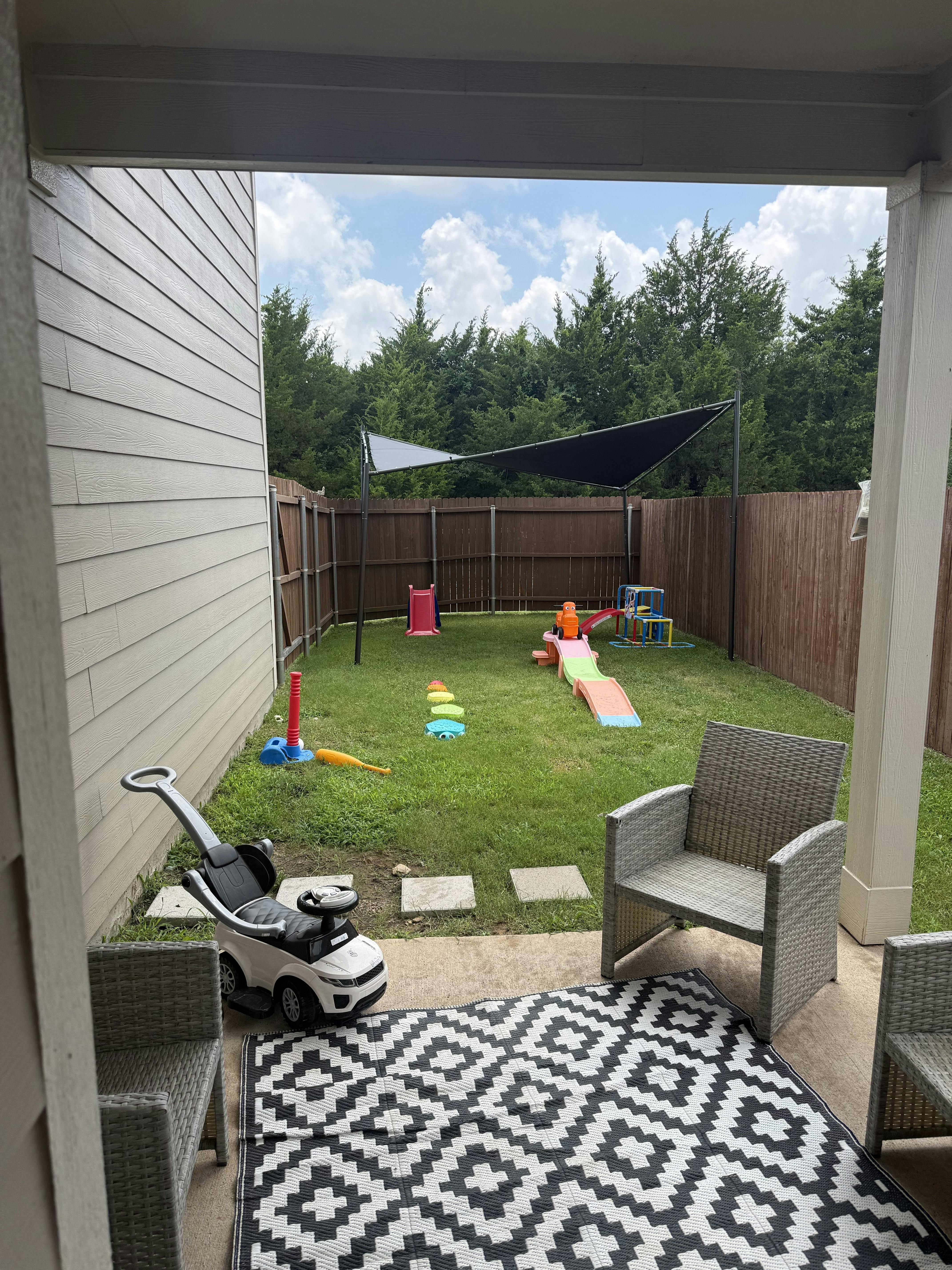 Playground equipment and toy car in a fenced backyard