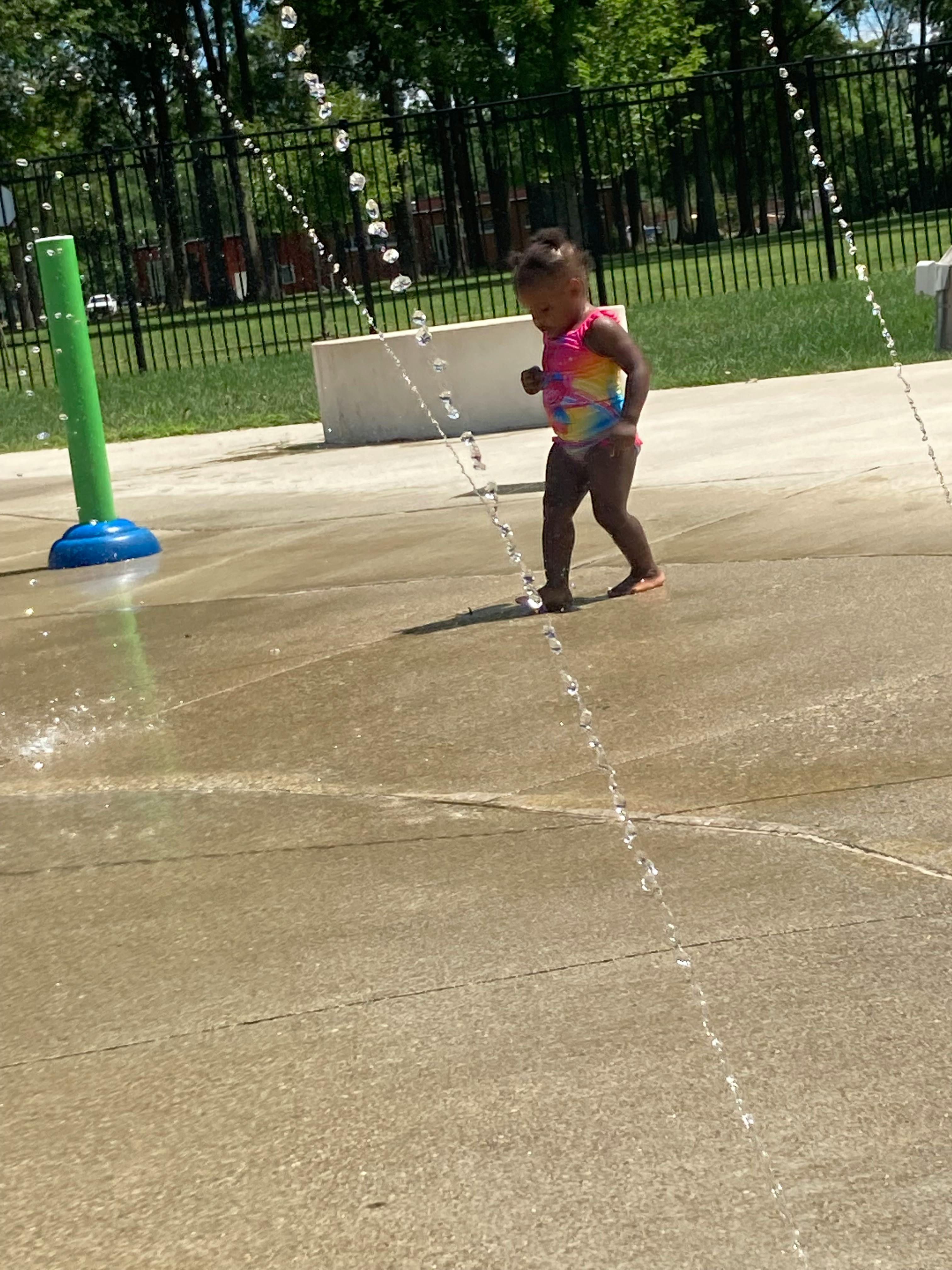 Child walking on a splash pad with water spraying