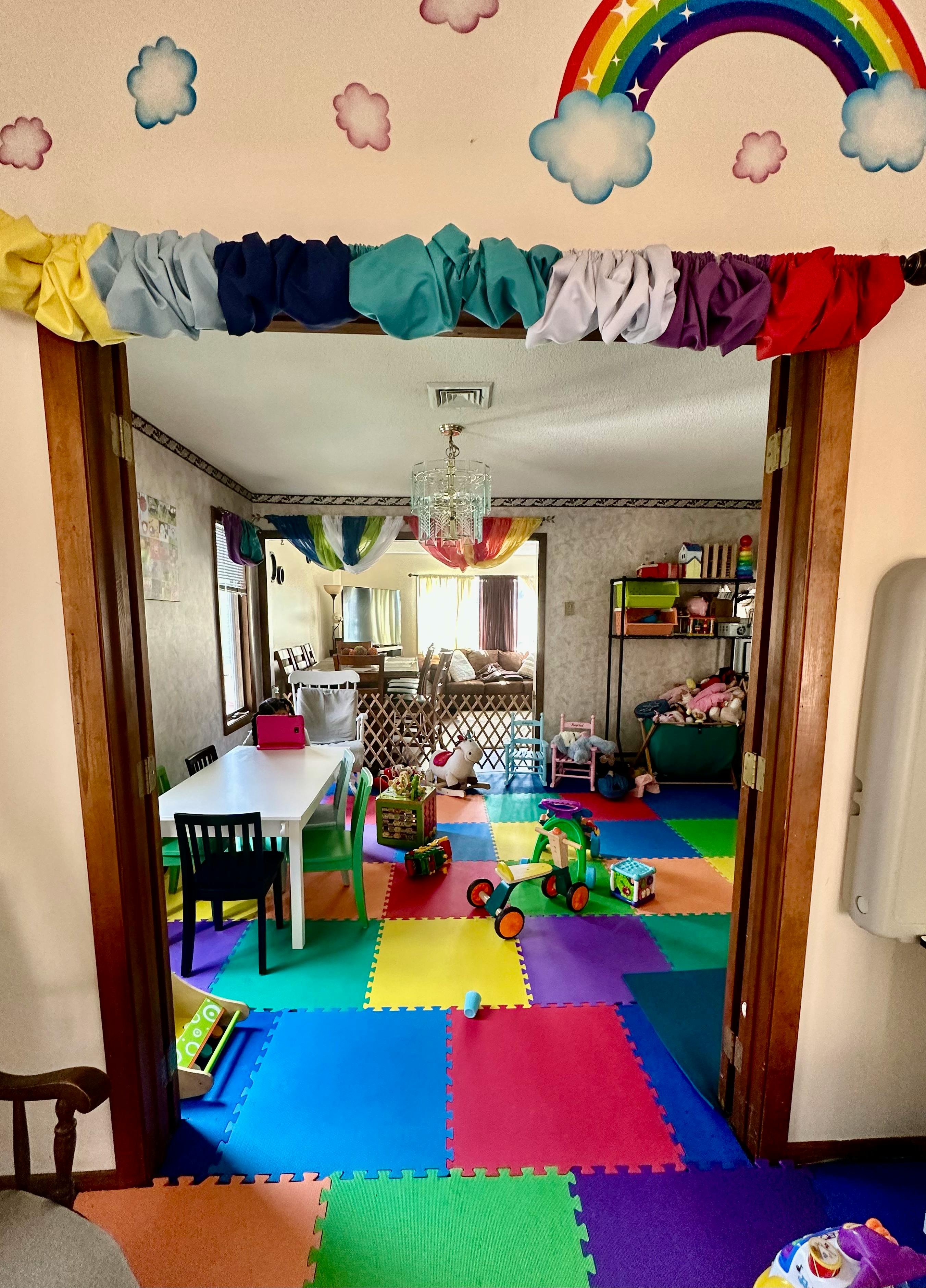 Playroom with colorful floor mats and toys, seen through a doorway