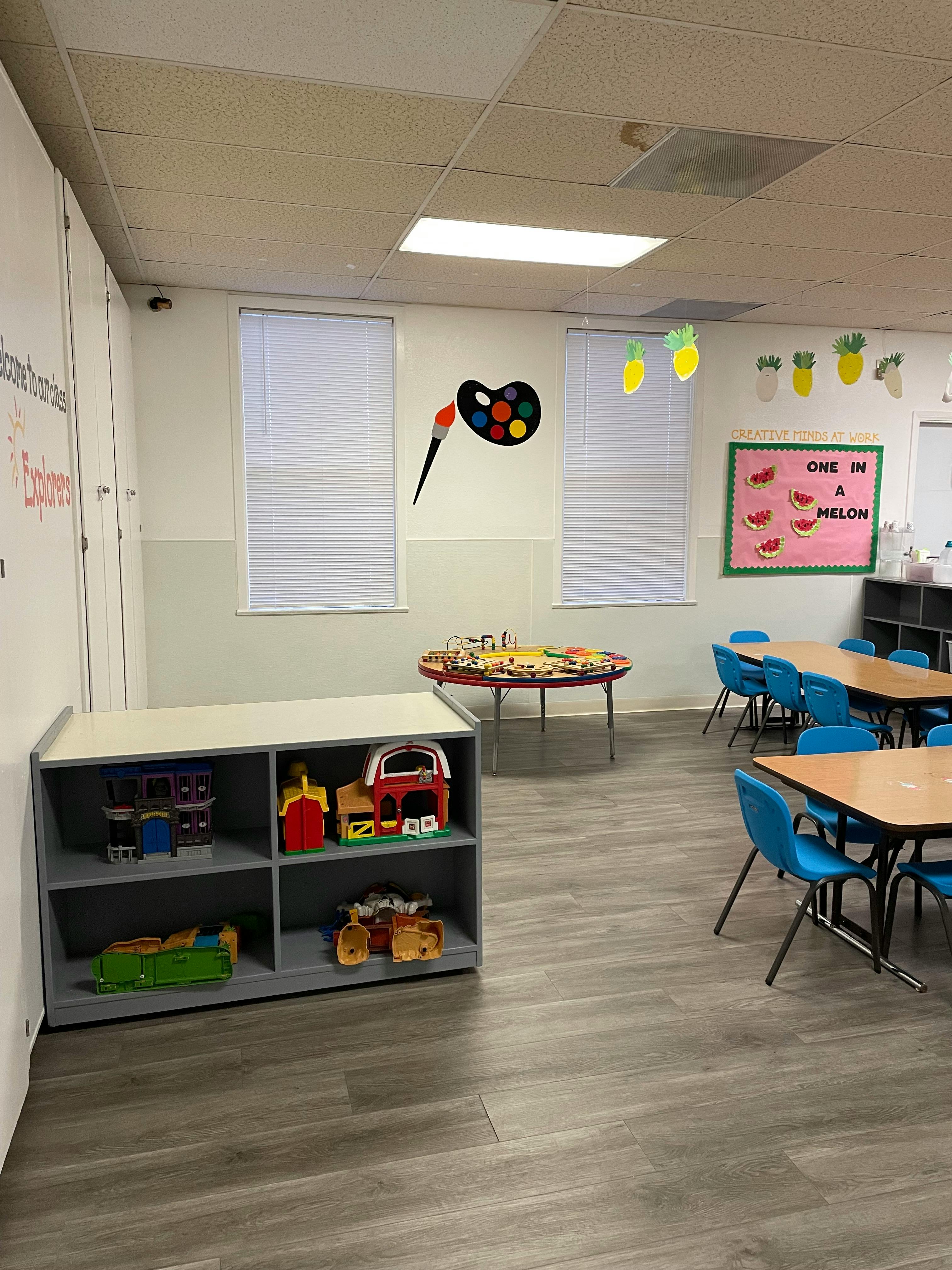 Classroom with tables, chairs, and a shelf with toys