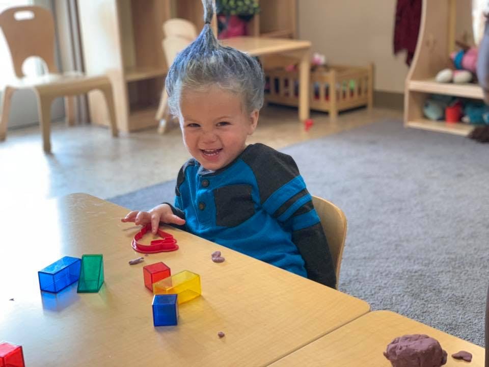 Child at a table with colorful blocks and playdough