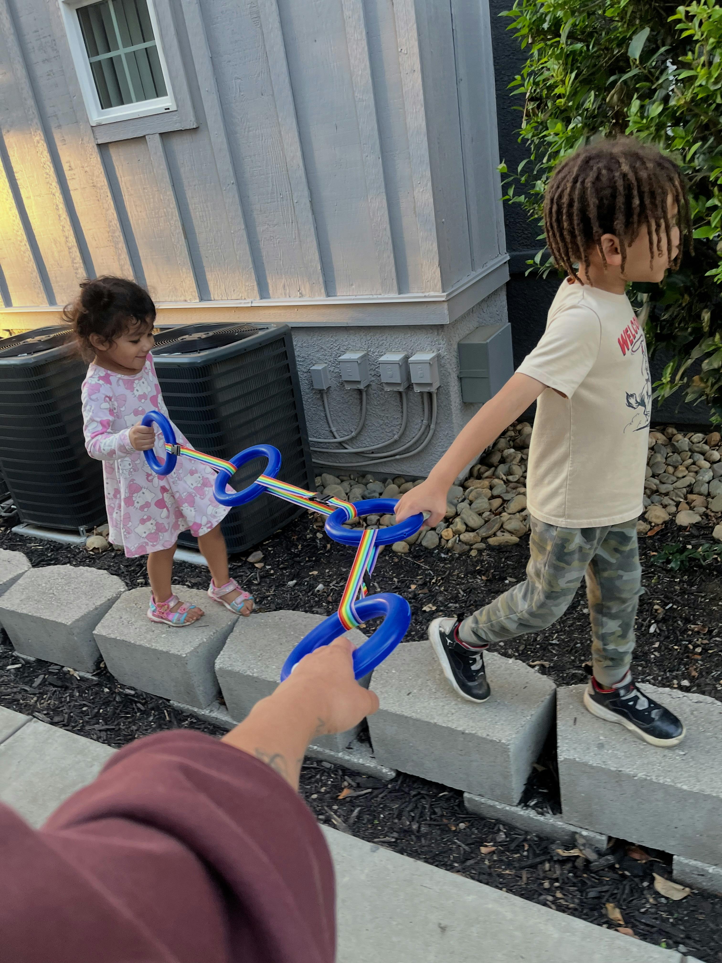 Two children playing with a toy with blue handles