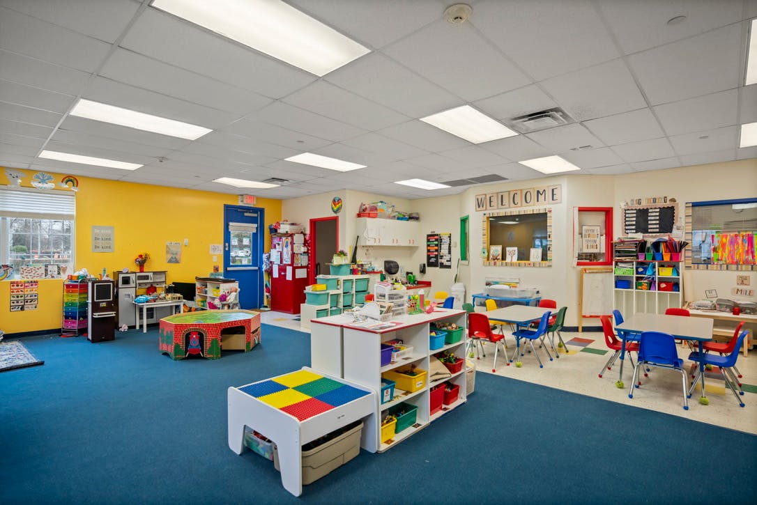 Empty classroom with colorful tables, chairs, and storage units