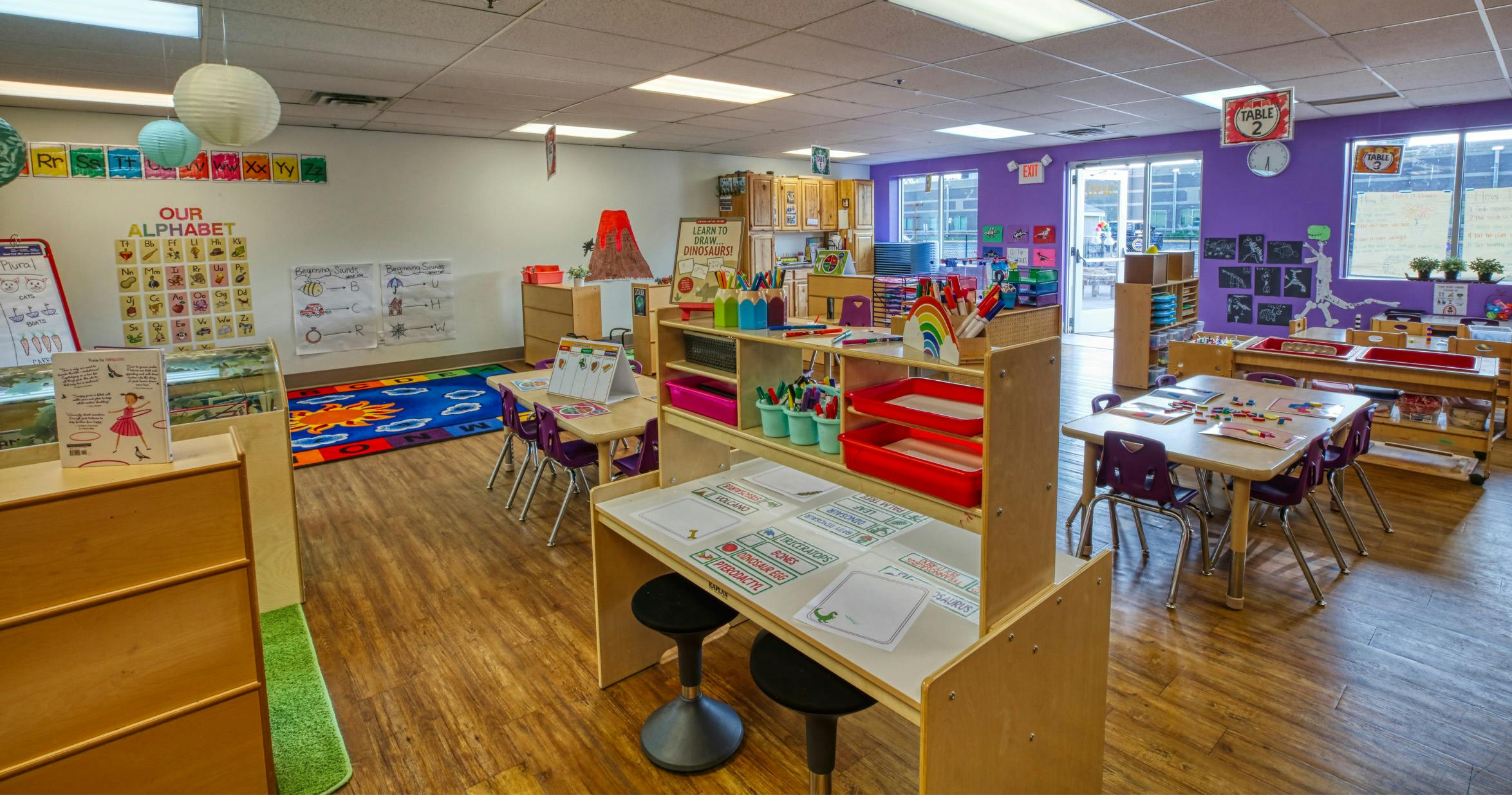 An empty early childhood classroom with purple walls and learning stations