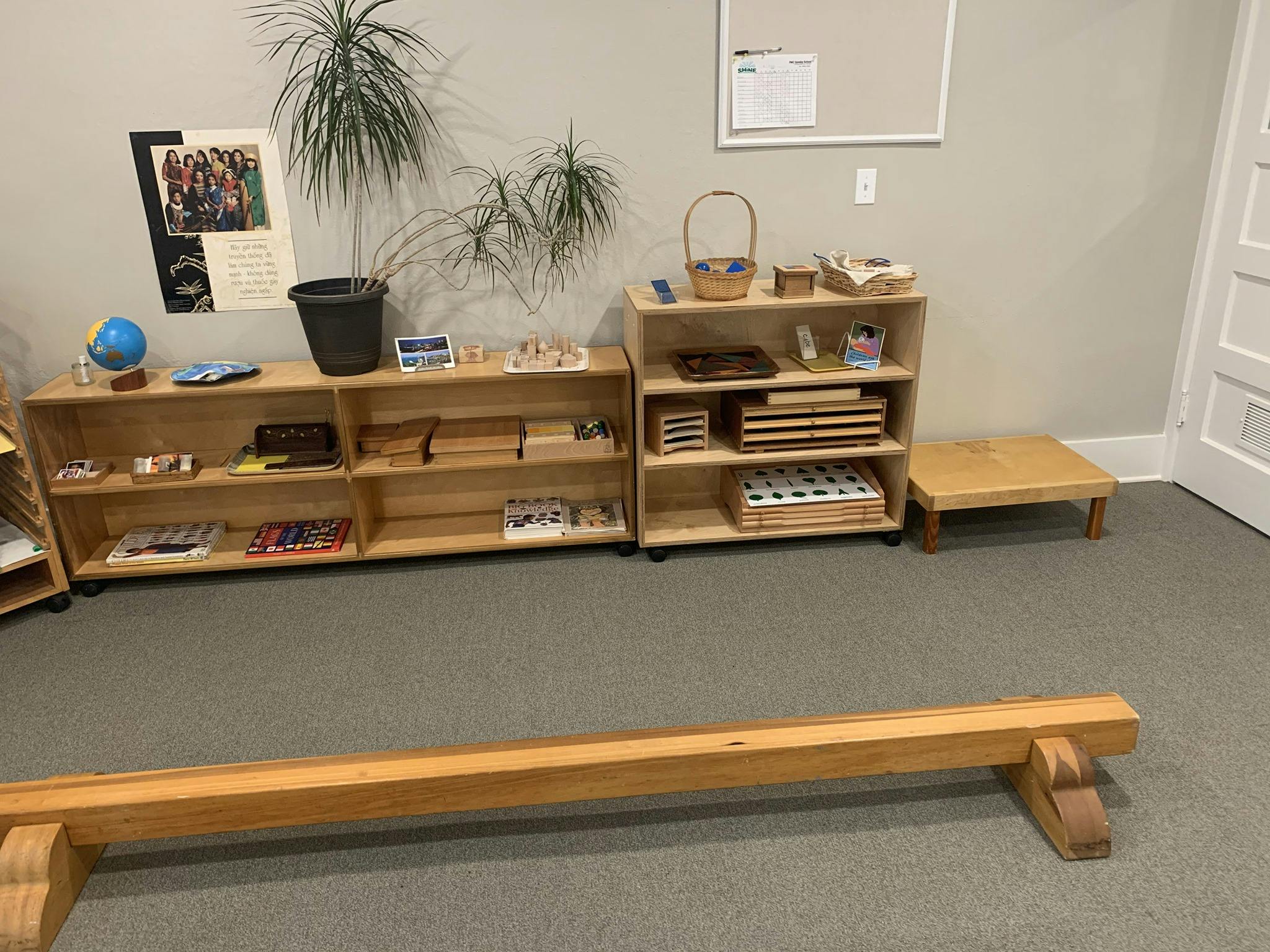 Classroom with wooden shelves, learning materials, and a balance beam