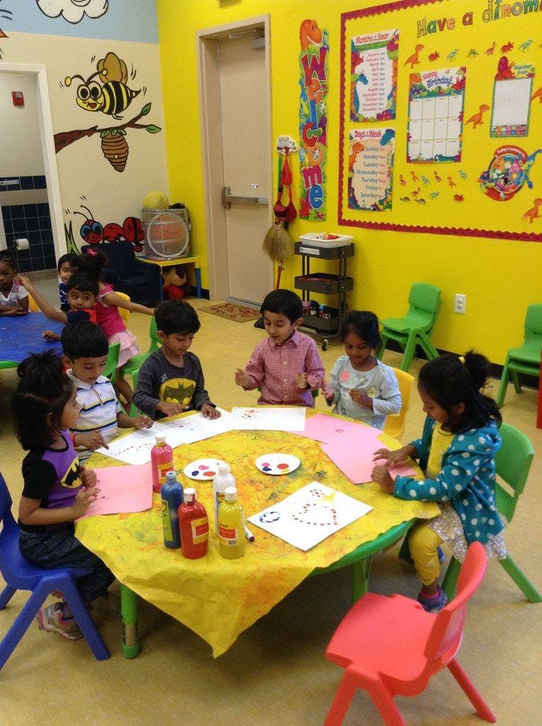 Children painting and drawing at a table in a classroom