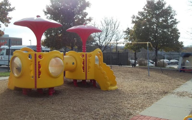Yellow and red playground set with slides and climbing areas on wood chips