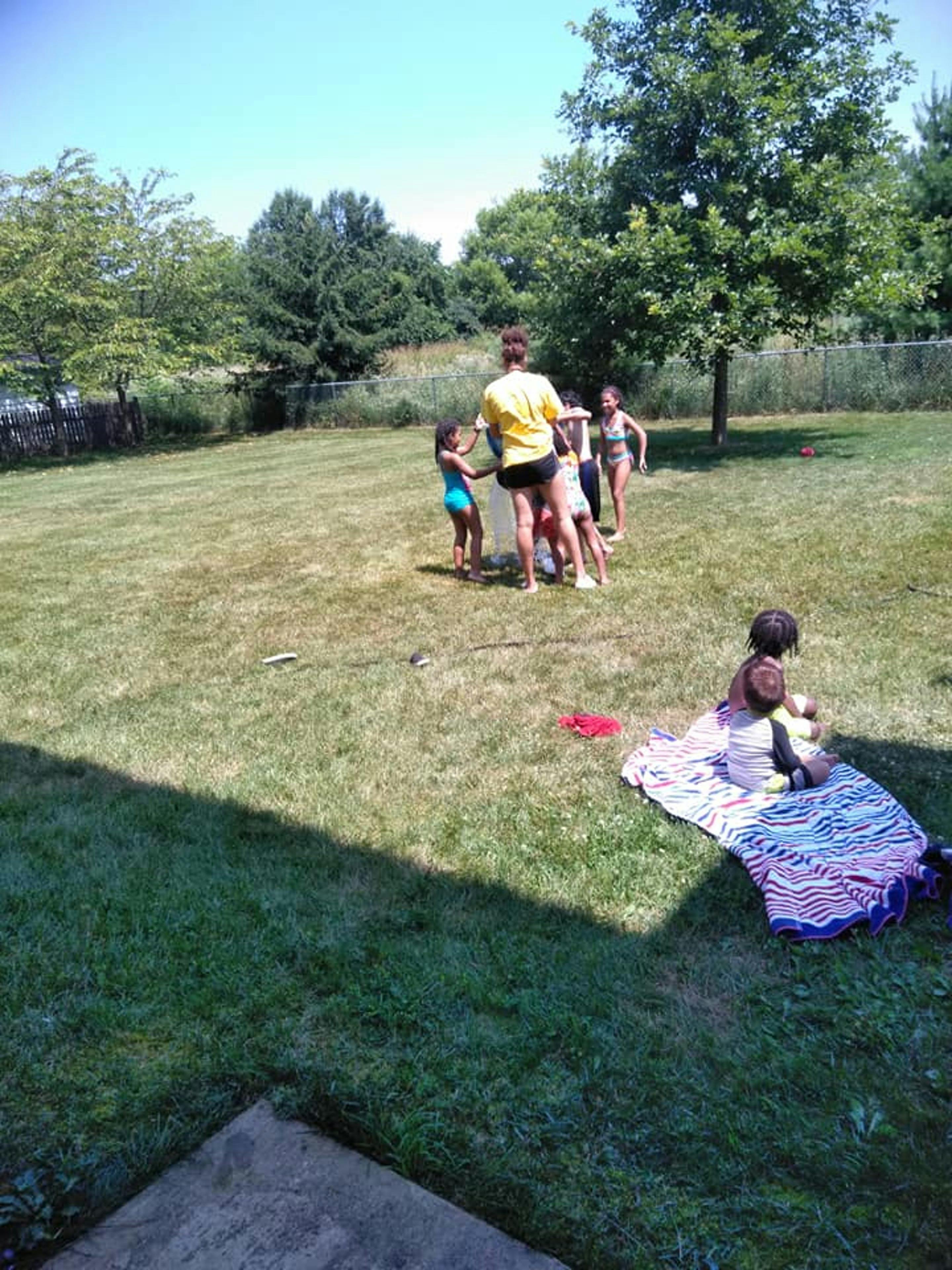 Person and children playing in a grassy yard