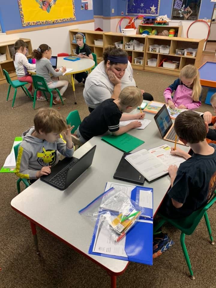 Adult and children working at tables in a classroom