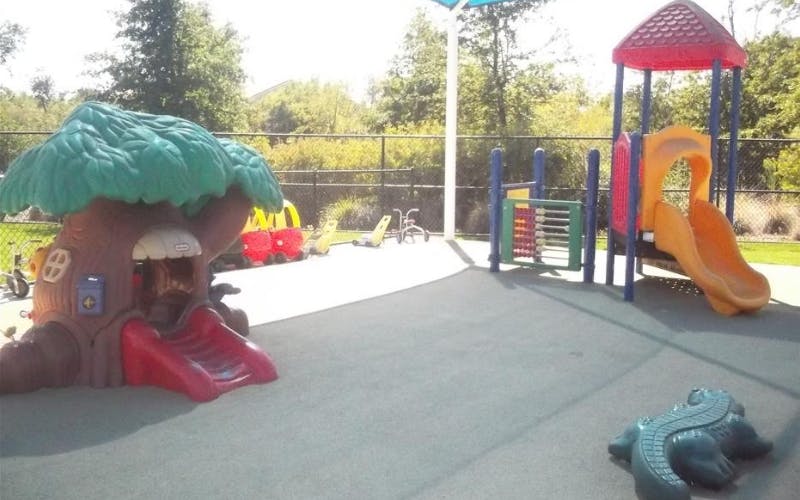 Playground with a treehouse play structure, slide, and other equipment