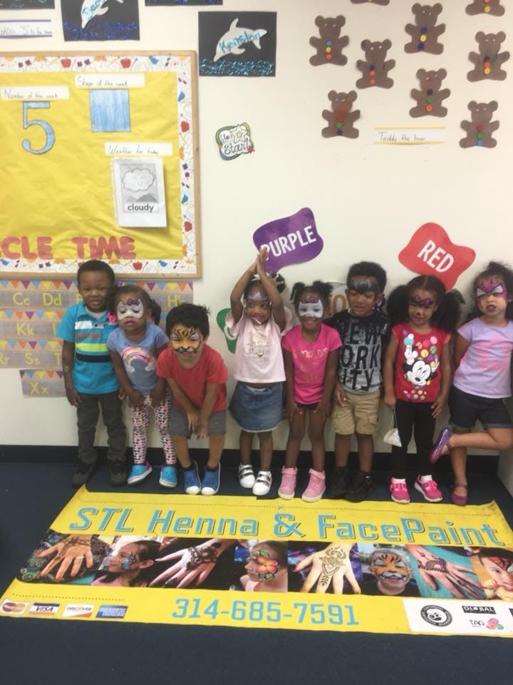 Children with face paint holding signs that say "Purple" and "Red"