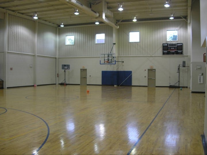 Empty indoor basketball court with wooden floor and scoreboard