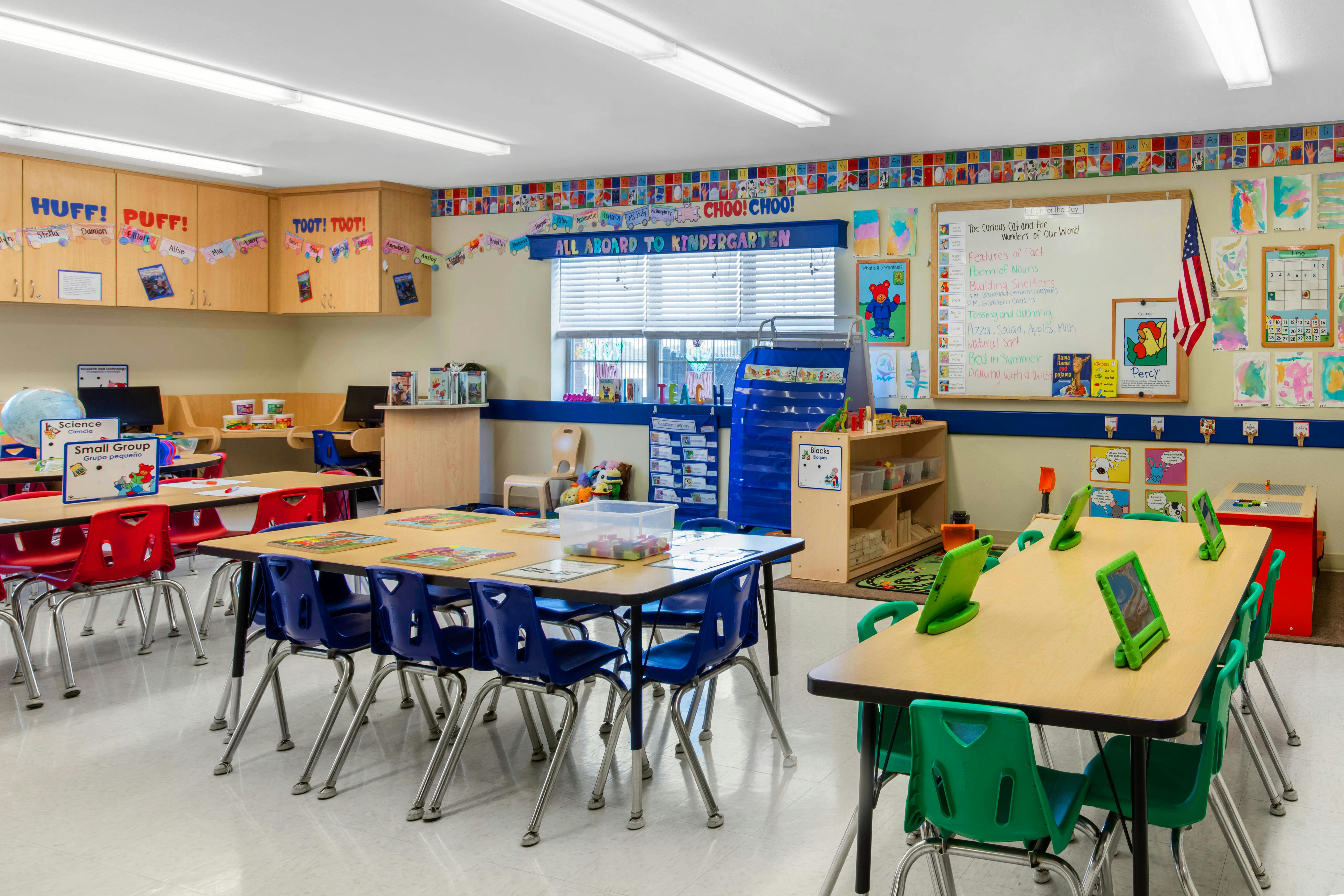 Empty colorful classroom with tables and chairs, decorations, and learning materials