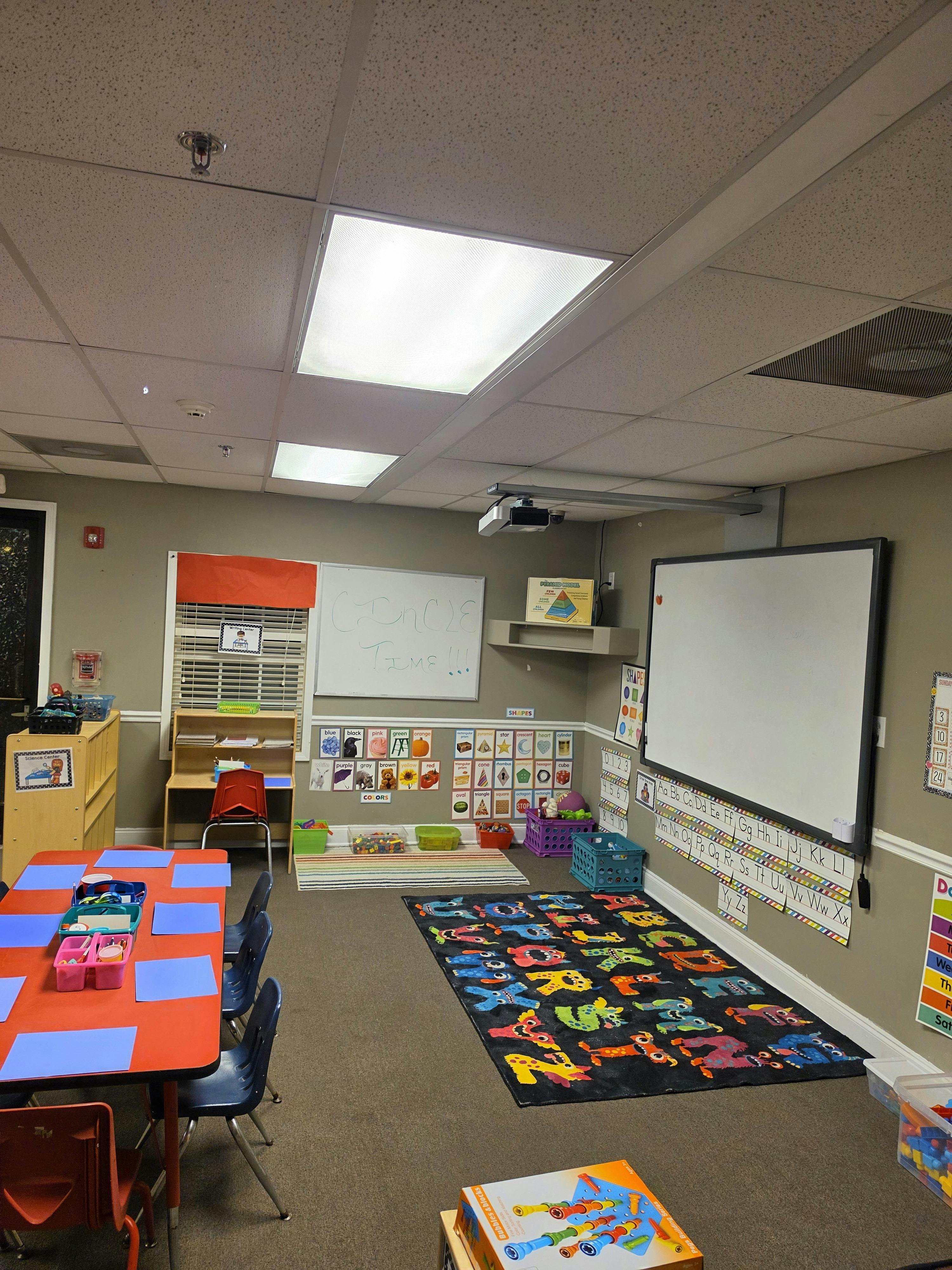 Classroom with child-sized tables and chairs, whiteboards, and colorful learning aids